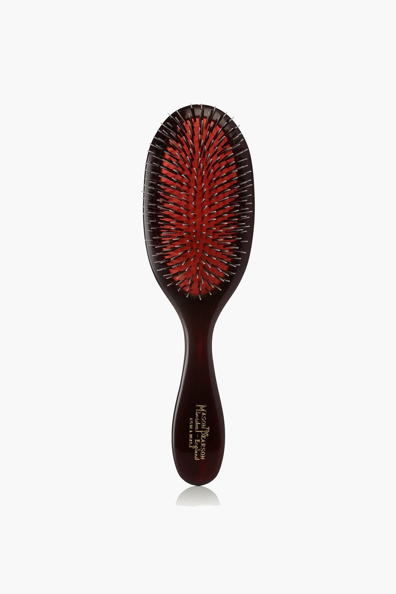 A Mason Pearson hair grooming tool featuring a dark handle, a red cushion, and a mix of black and silver bristles.