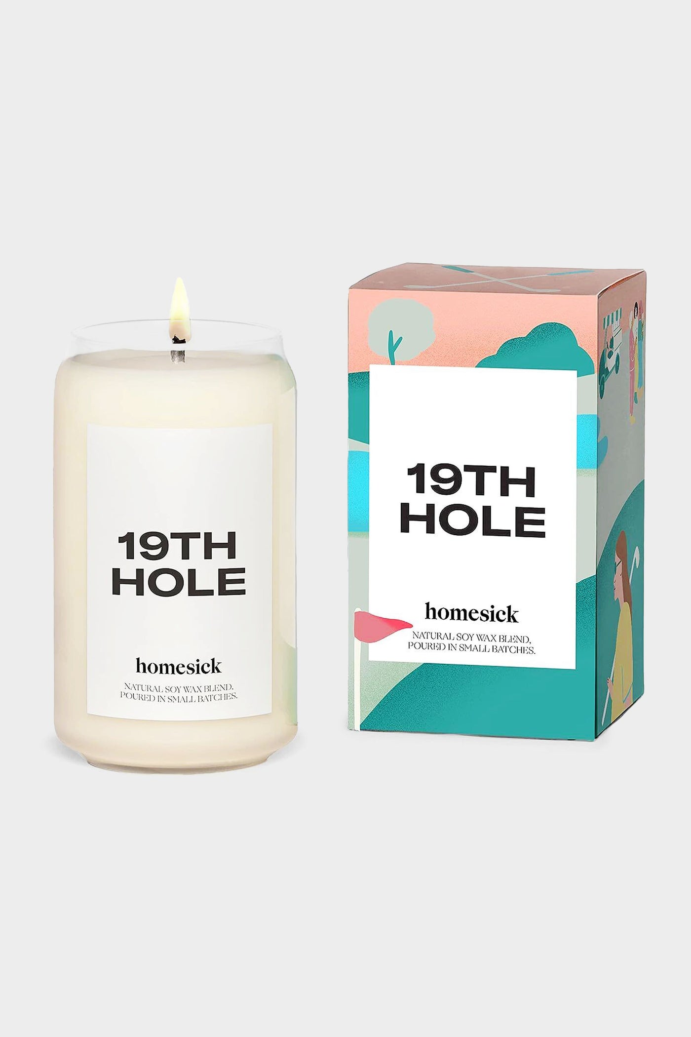 A lit white Homesick Candles 19TH HOLE soy candle sits beside its illustrated box featuring outdoor scenery—an ideal home fragrance or golfer gift.