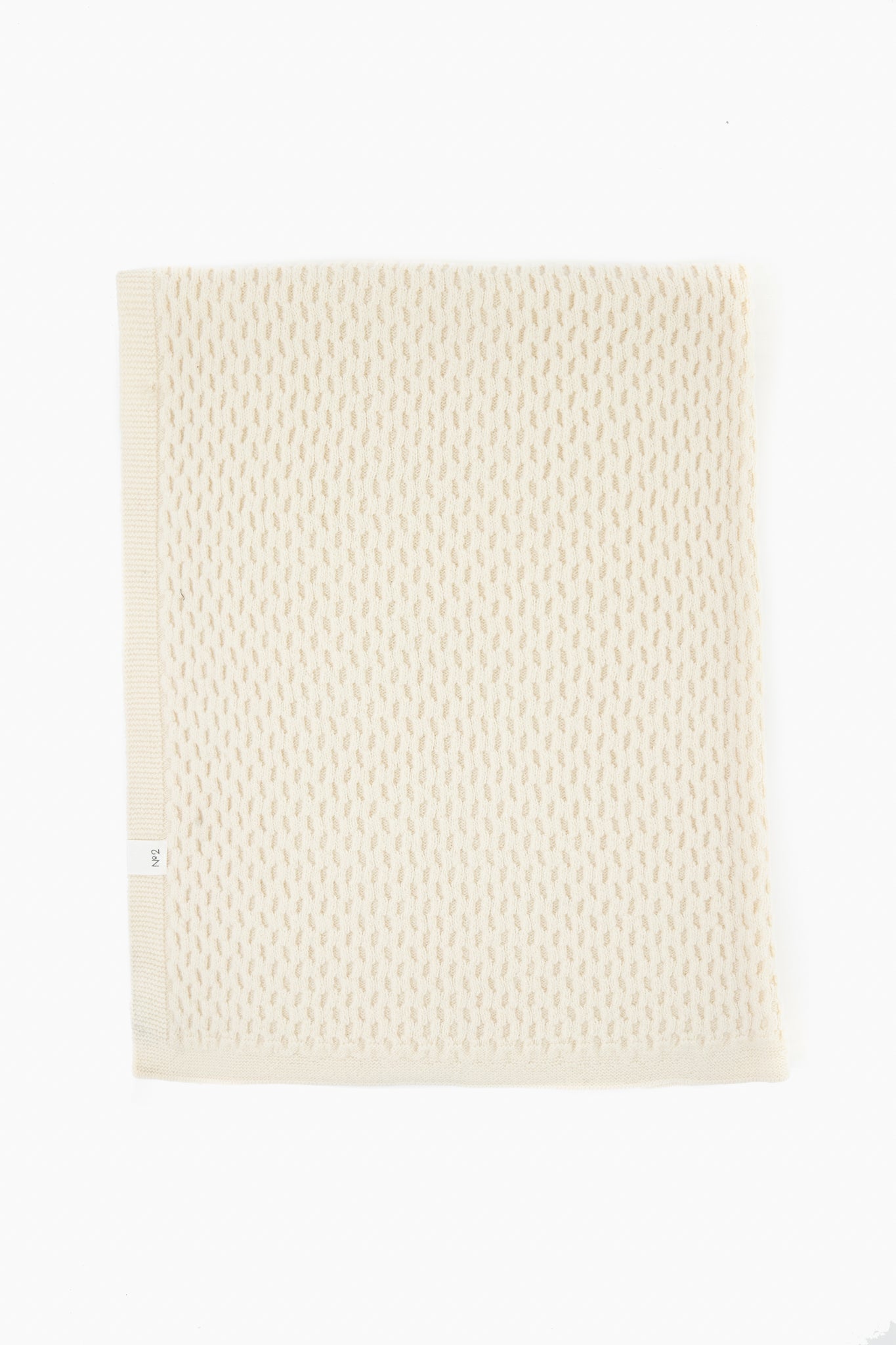 A folded off-white textured knit blanket by baa, crafted from Hudson Valley Cormo Sheep wool, highlights the luxury of heirloom knits.