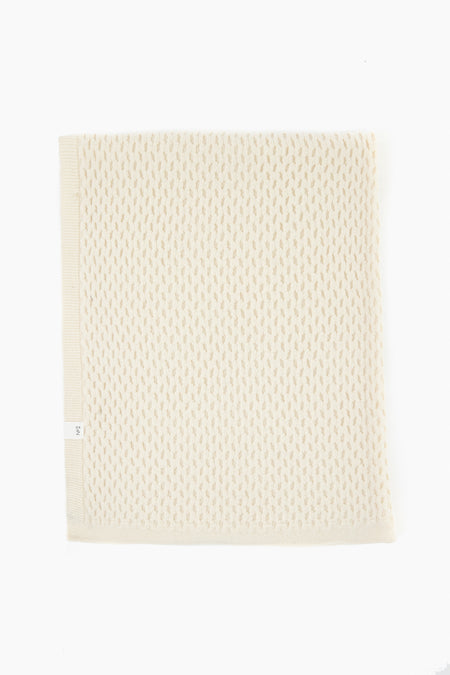 A folded off-white textured knit blanket by baa, crafted from Hudson Valley Cormo Sheep wool, highlights the luxury of heirloom knits.