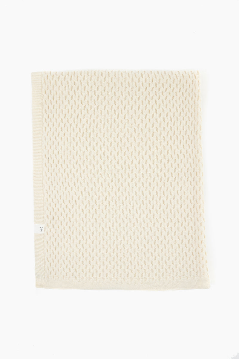 A folded off-white textured knit blanket by baa, crafted from Hudson Valley Cormo Sheep wool, highlights the luxury of heirloom knits.