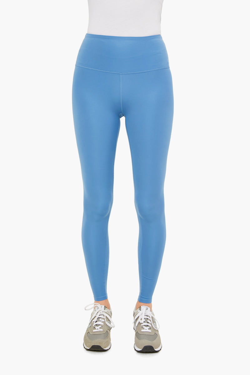 A person wearing Varley sky blue high rise leggings with 4-way stretch, a white top, and gray sneakers.