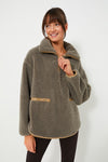 A woman wears a Tuckernuck cozy gray fleece pullover featuring a zip collar, front pockets, and faux leather trim.