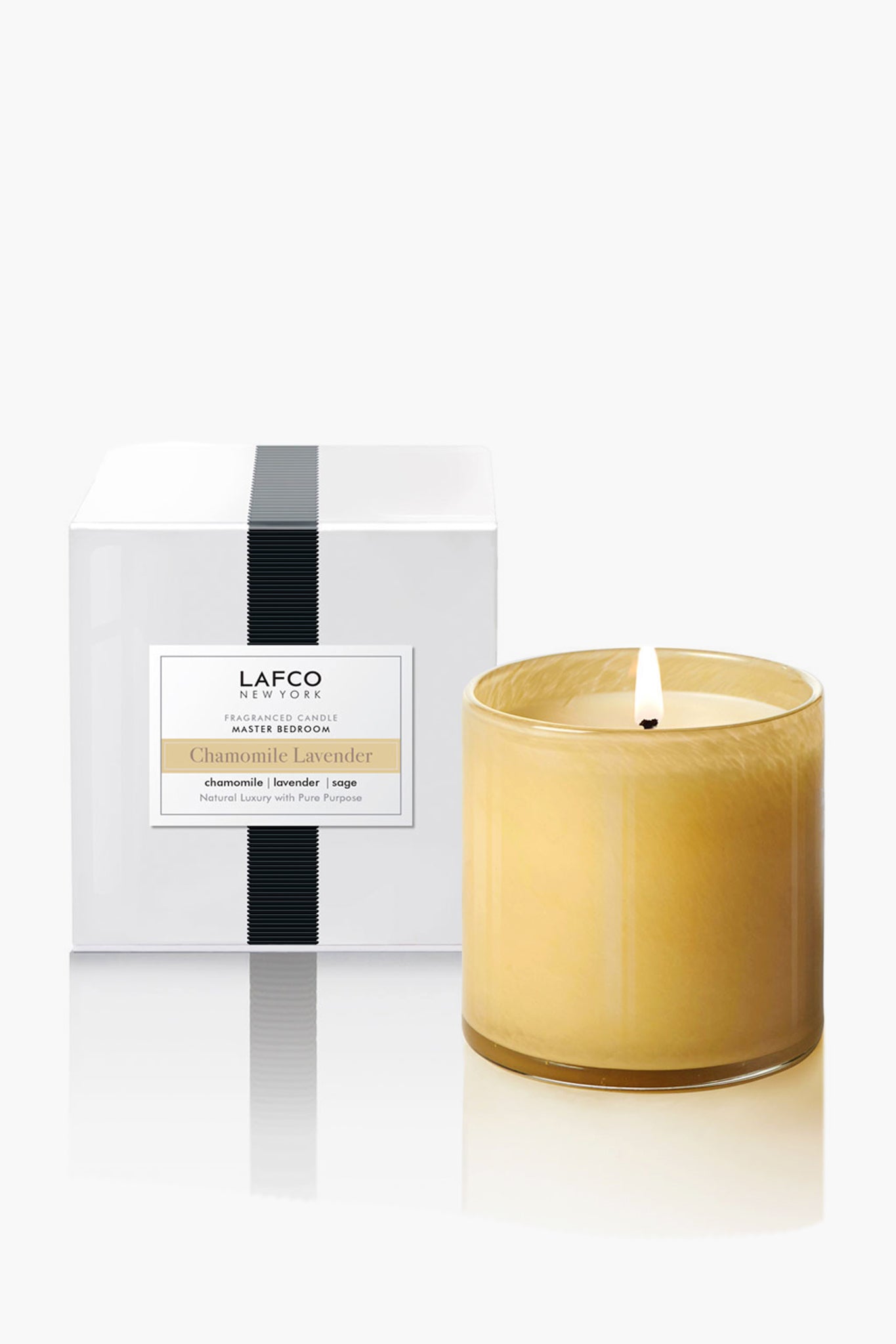 A yellow glass Chamomile Lavender candle by LAFCO New York glows beside its elegant white box with a black stripe, showcasing the refined charm of hand-poured home fragrances.
