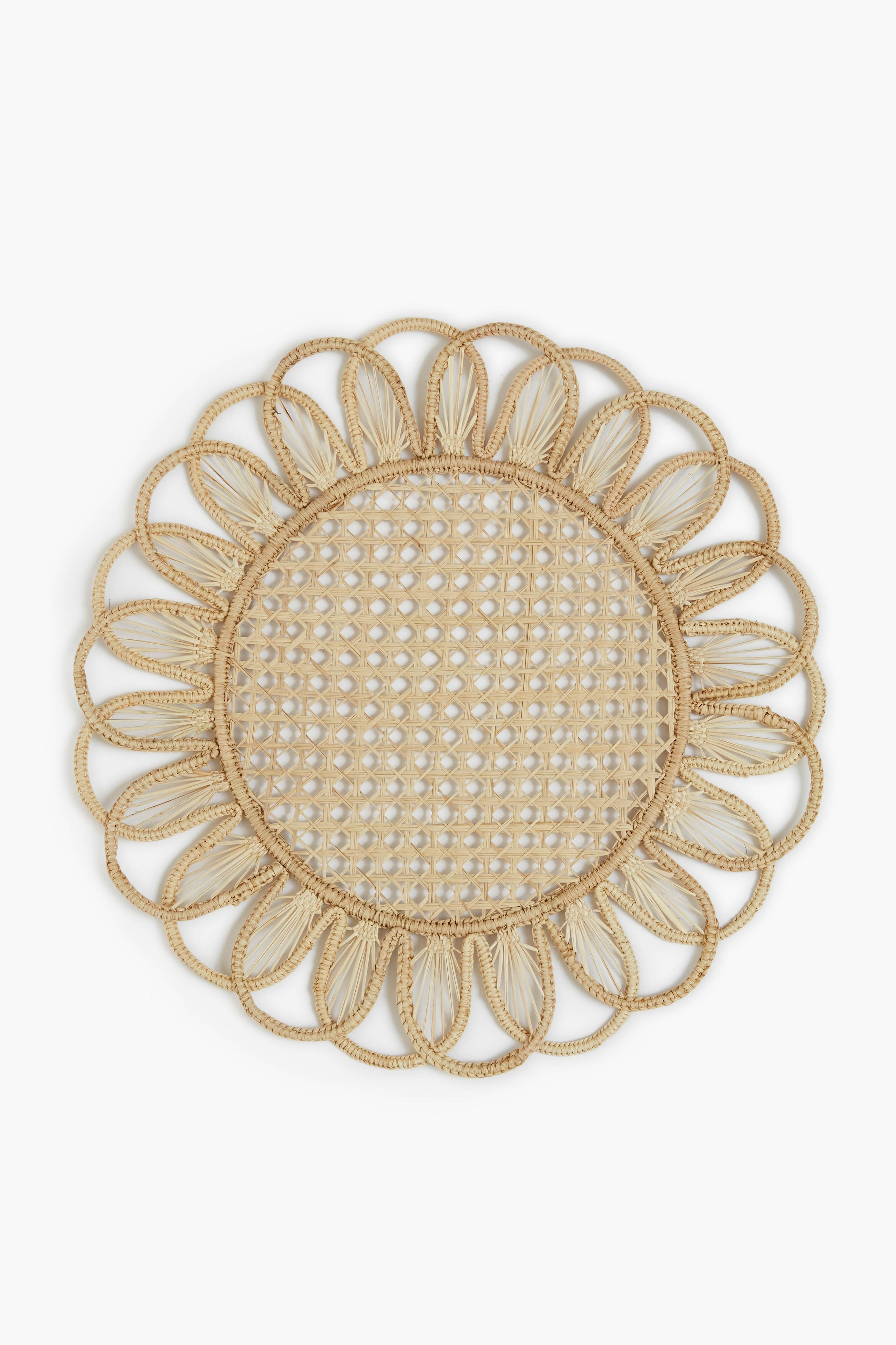 Expertly crafted by Coro Cora, this round woven Iraca palm placemat features a floral-inspired scalloped edge and an open lattice center, showcasing the artistry of Colombian accessories.