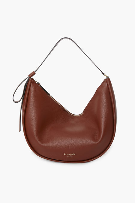 A brown pebbled leather Kate Spade New York shoulder bag with a single strap, zipper closure, and the brand’s logo on the front.