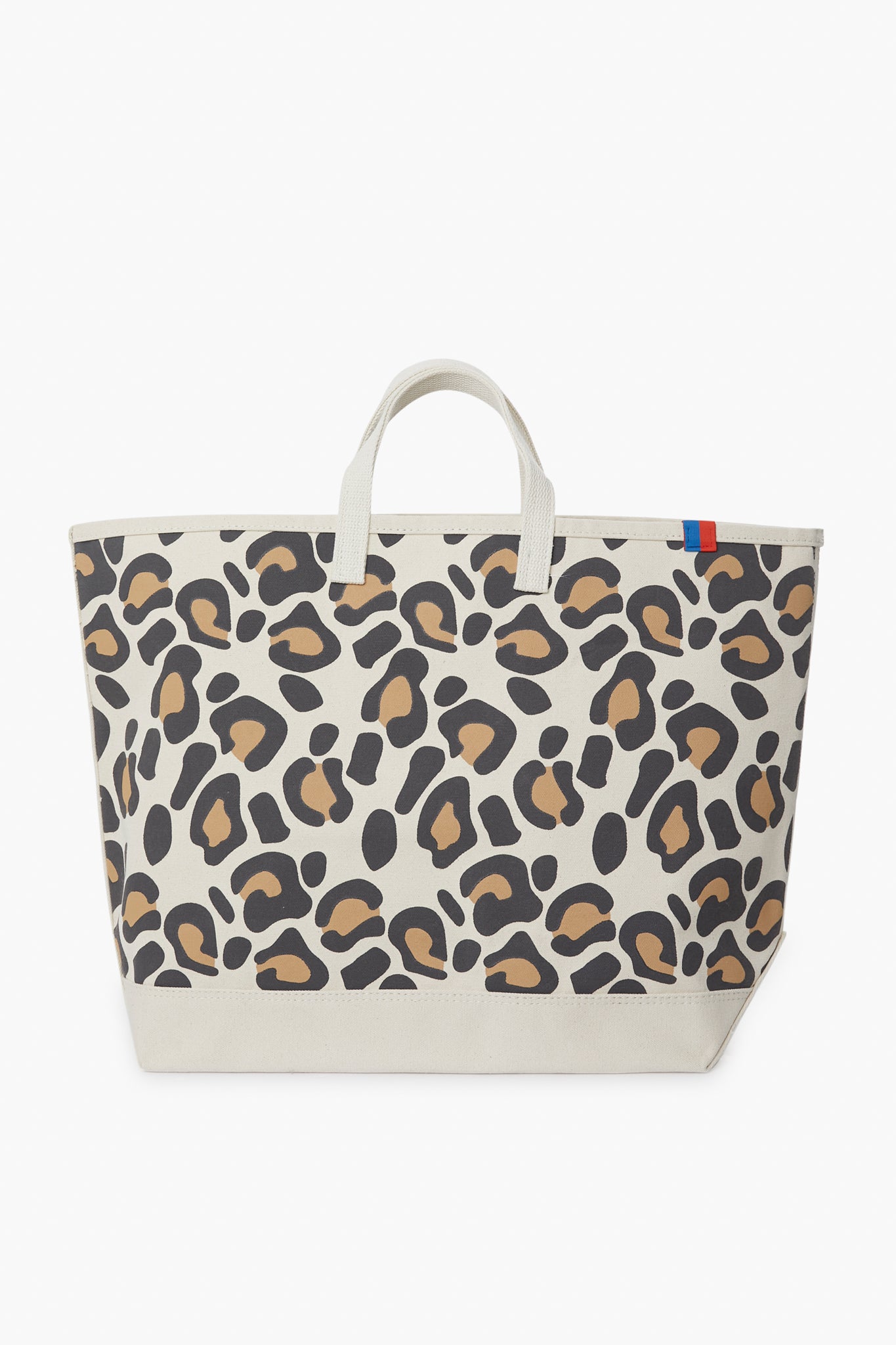 The KULE Large Leopard Tote features short handles, a beige, brown, and black print, and a small blue and red tab on the upper edge—perfect as a stylish daily carry-all.