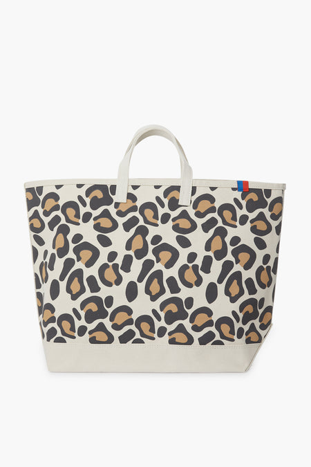 The KULE Large Leopard Tote features short handles, a beige, brown, and black print, and a small blue and red tab on the upper edge—perfect as a stylish daily carry-all.