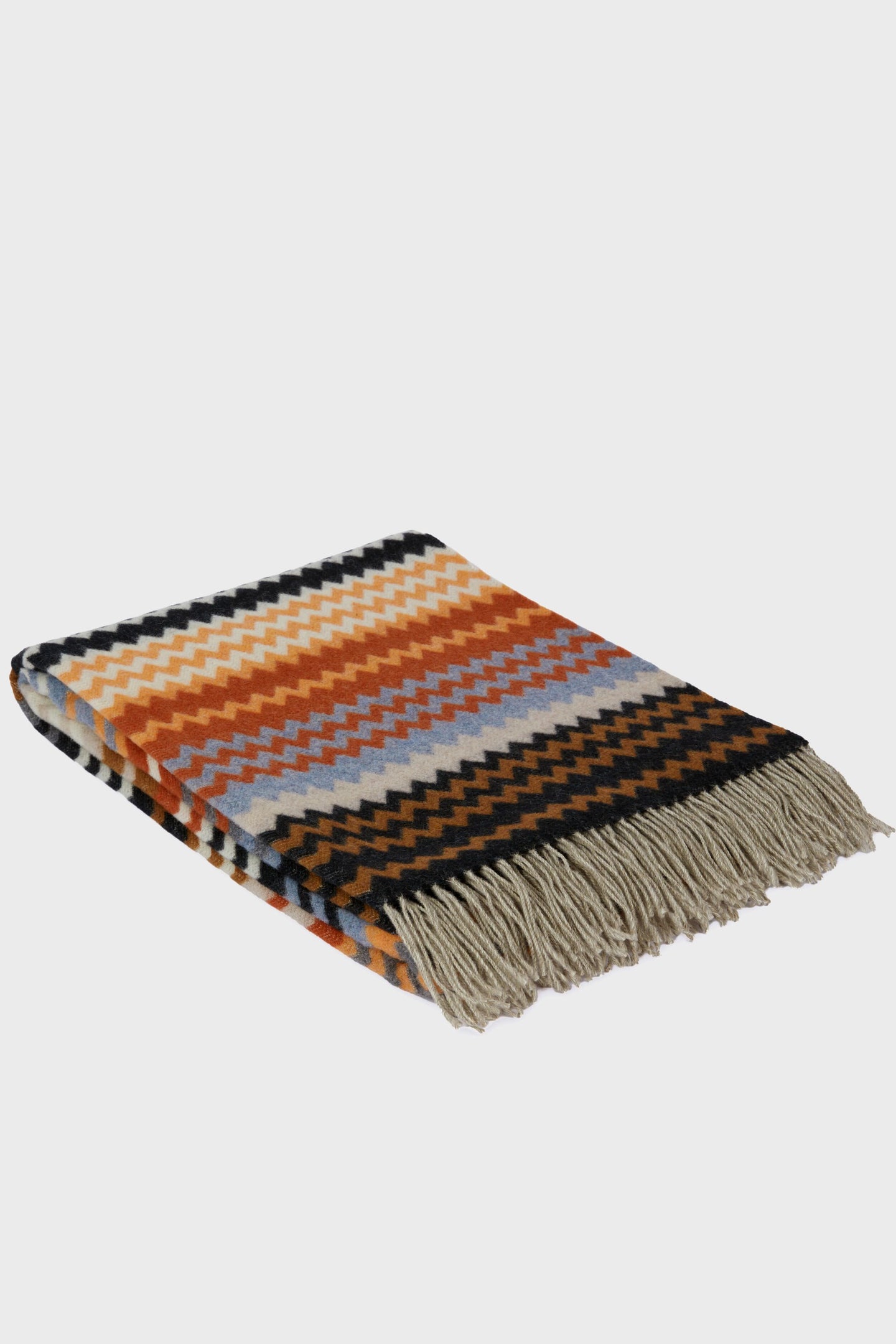 Orange, yellow, black, and blue chevron throw with beige fringes on one end from Missoni Home—luxurious zigzag patterned decor for your space.