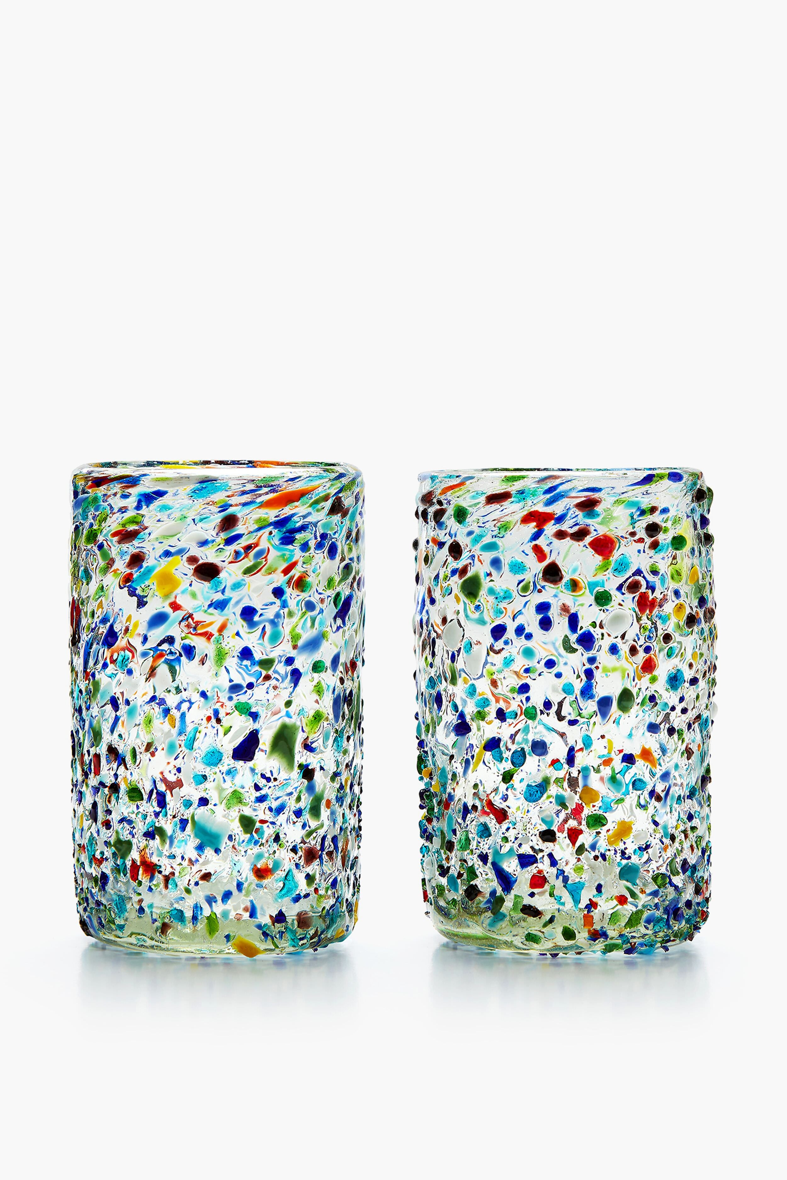 Two hand-blown Chefanie Confetti Glasses, featuring a textured surface with multicolored speckles in blue, green, red, and yellow, sit side by side—ideal for a cheerful housewarming gift.