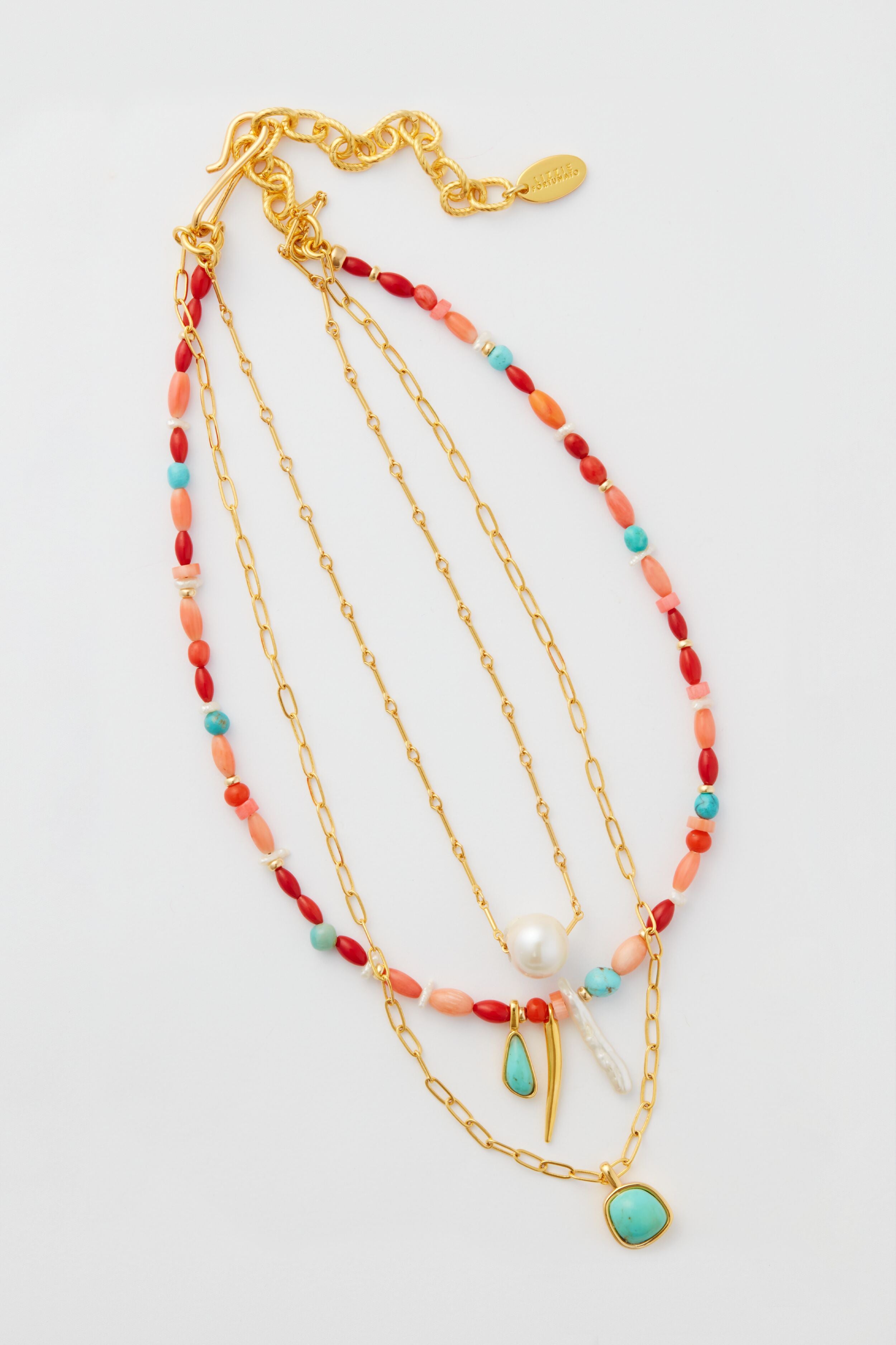 Three gold-plated chain necklaces by Lizzie Fortunato, adorned with colorful beads, pearls, and turquoise pendants, create a chic multi-strand necklace look.