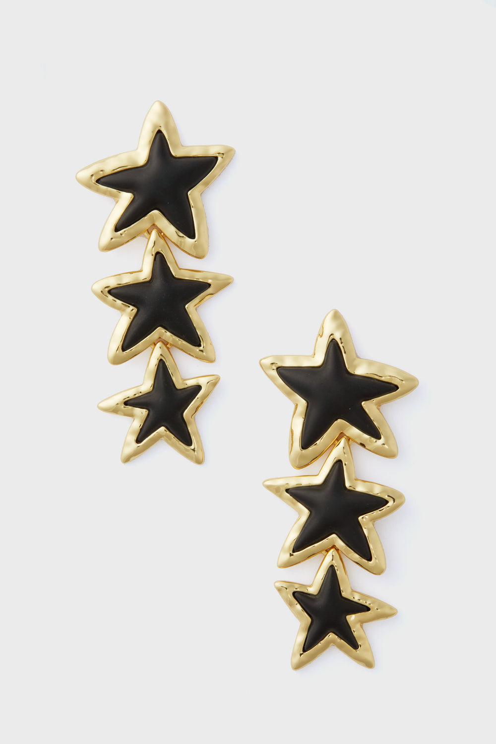 Gold and black star-shaped drop earrings with three stacked stars on each earring. The Tuckernuck Jewelry Noir Stars Odette Earrings are perfect statement pieces to add a bold touch to any outfit.