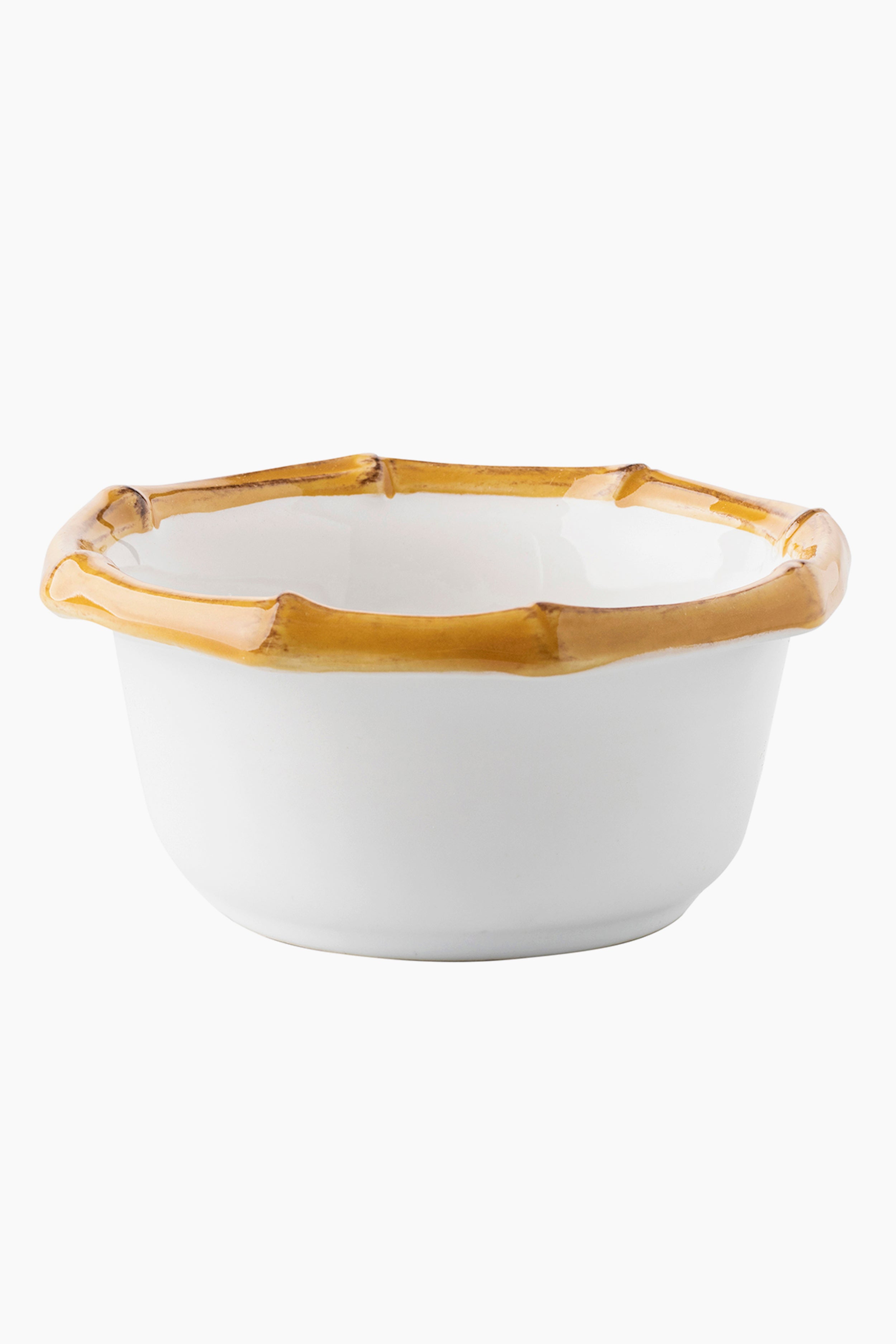 A white stoneware bowl by Juliska with a hexagonal bamboo-inspired rim and a glossy tan edge.