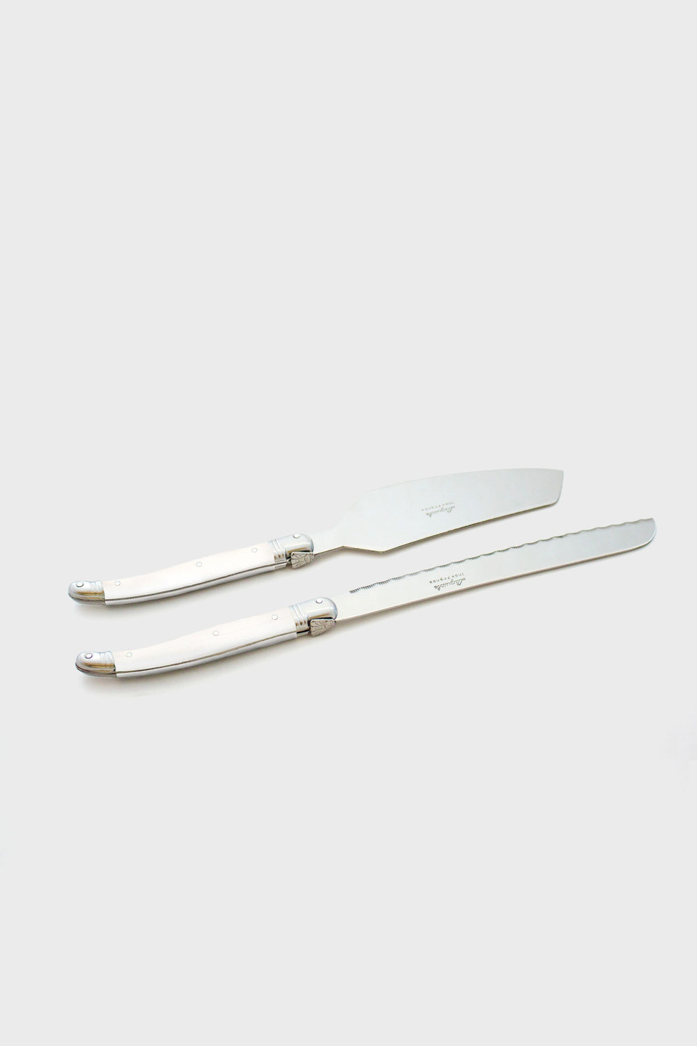 Two stainless steel cake knives with silver handles are placed parallel to each other, reflecting the elegant design of Laguiole flatware.
