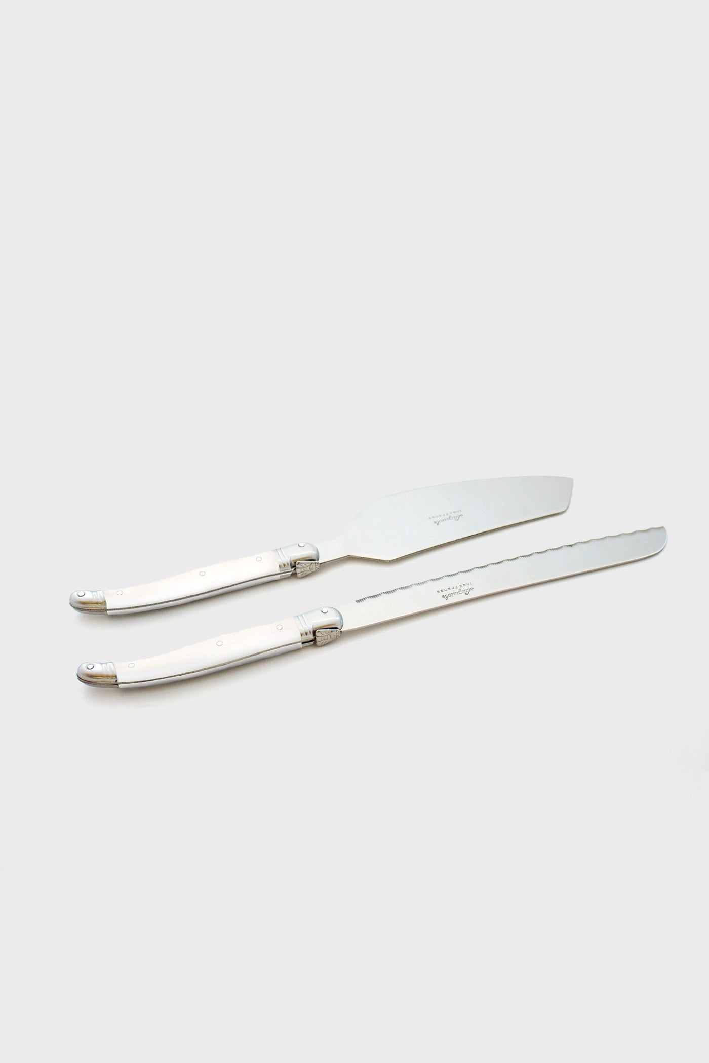 Two stainless steel cake knives with silver handles are placed parallel to each other, reflecting the elegant design of Laguiole flatware.