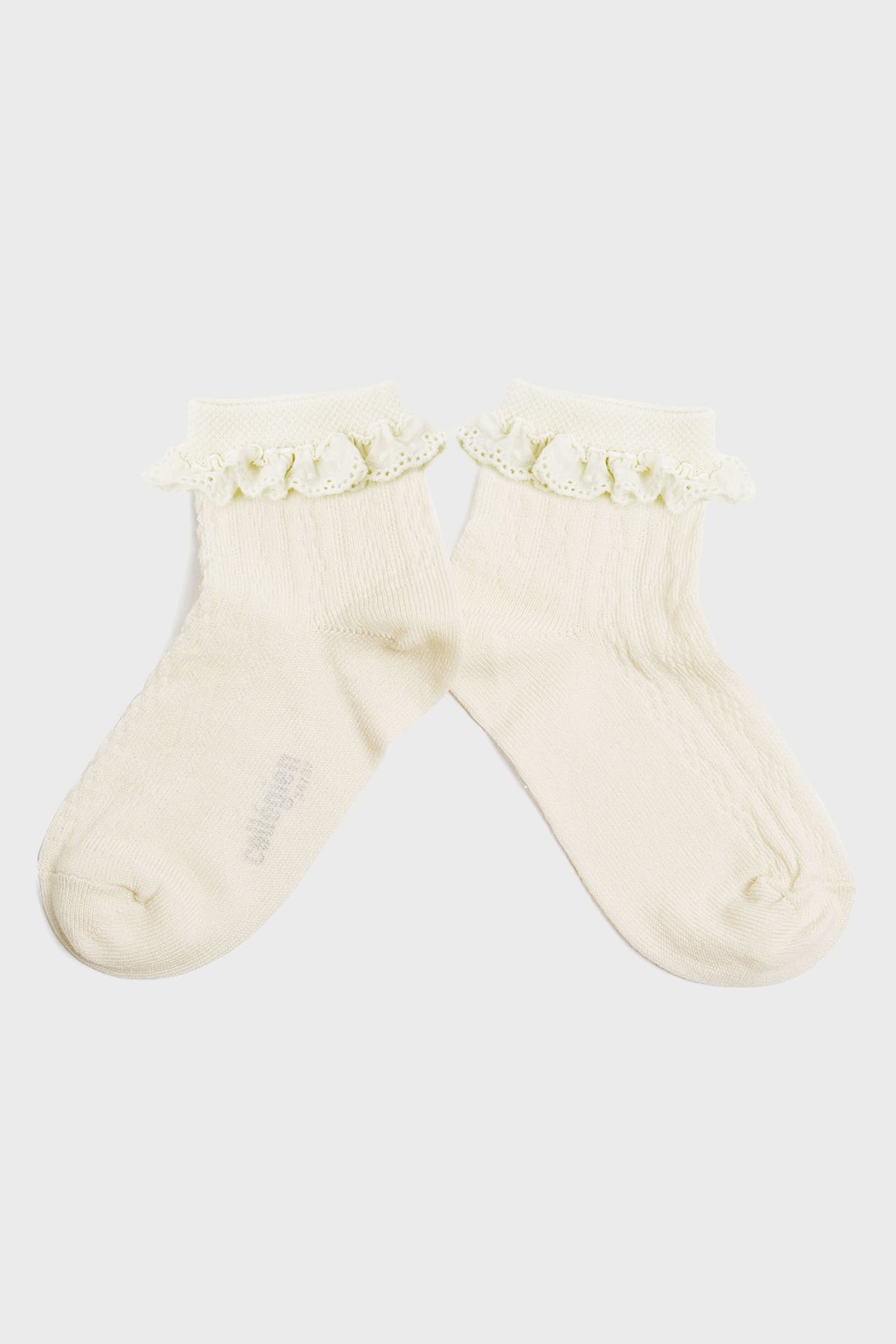 A pair of cream-colored kids’ socks from Collegien Tights, made with Egyptian cotton and finished with a delicate broderie Anglaise ruffle trim at the top.