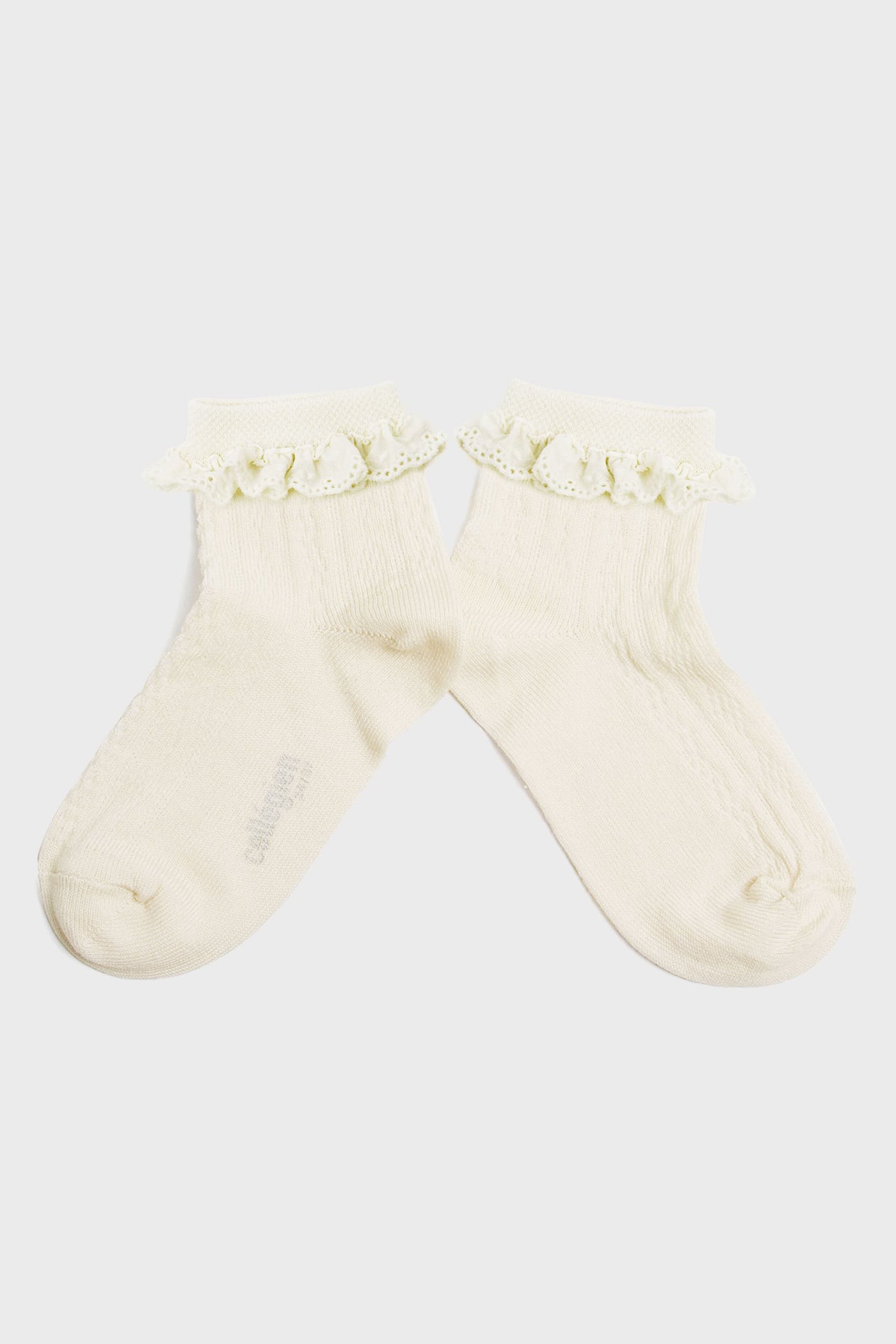 A pair of cream-colored kids’ socks from Collegien Tights, made with Egyptian cotton and finished with a delicate broderie Anglaise ruffle trim at the top.