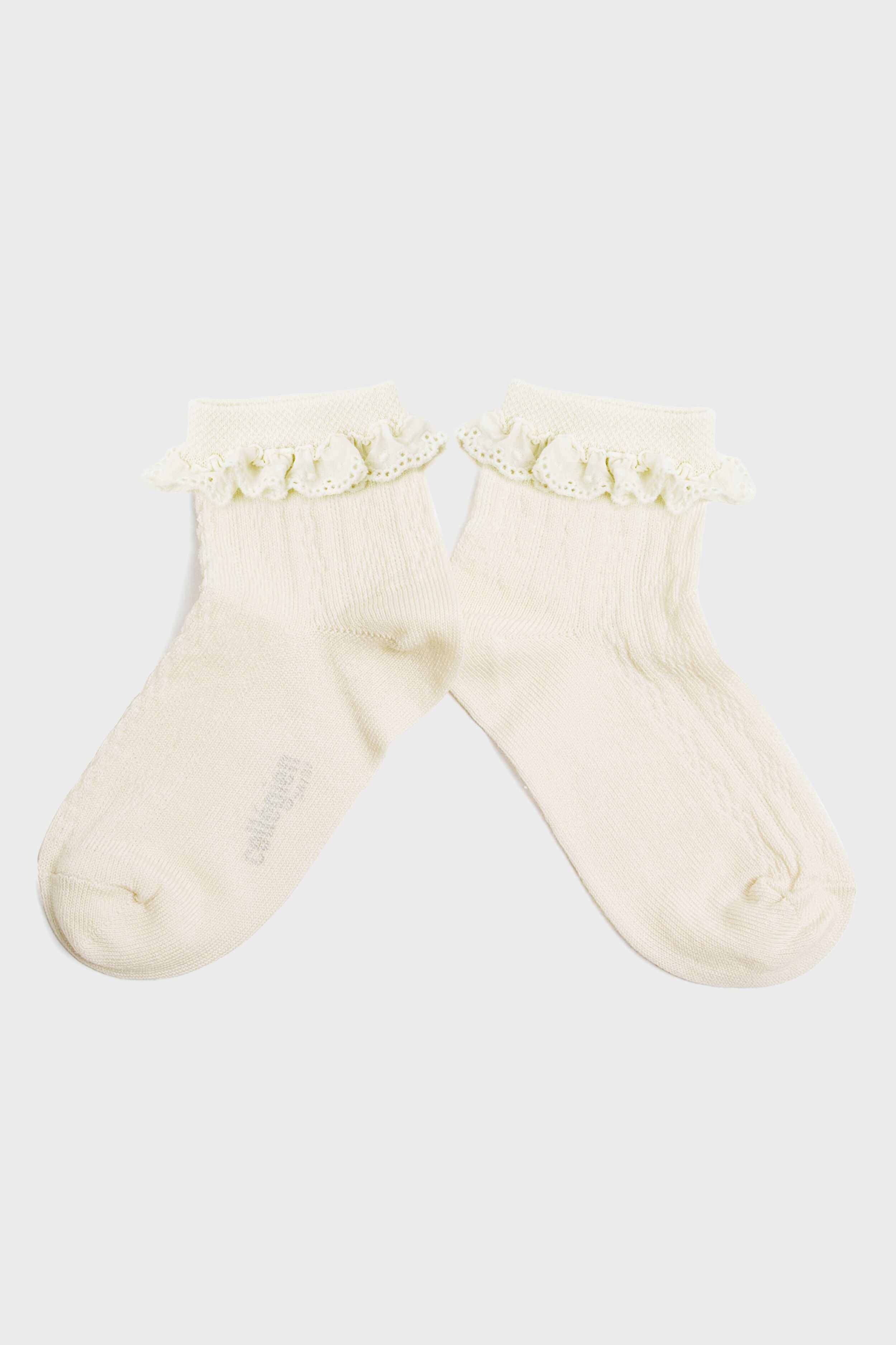 A pair of cream-colored kids’ socks from Collegien Tights, made with Egyptian cotton and finished with a delicate broderie Anglaise ruffle trim at the top.