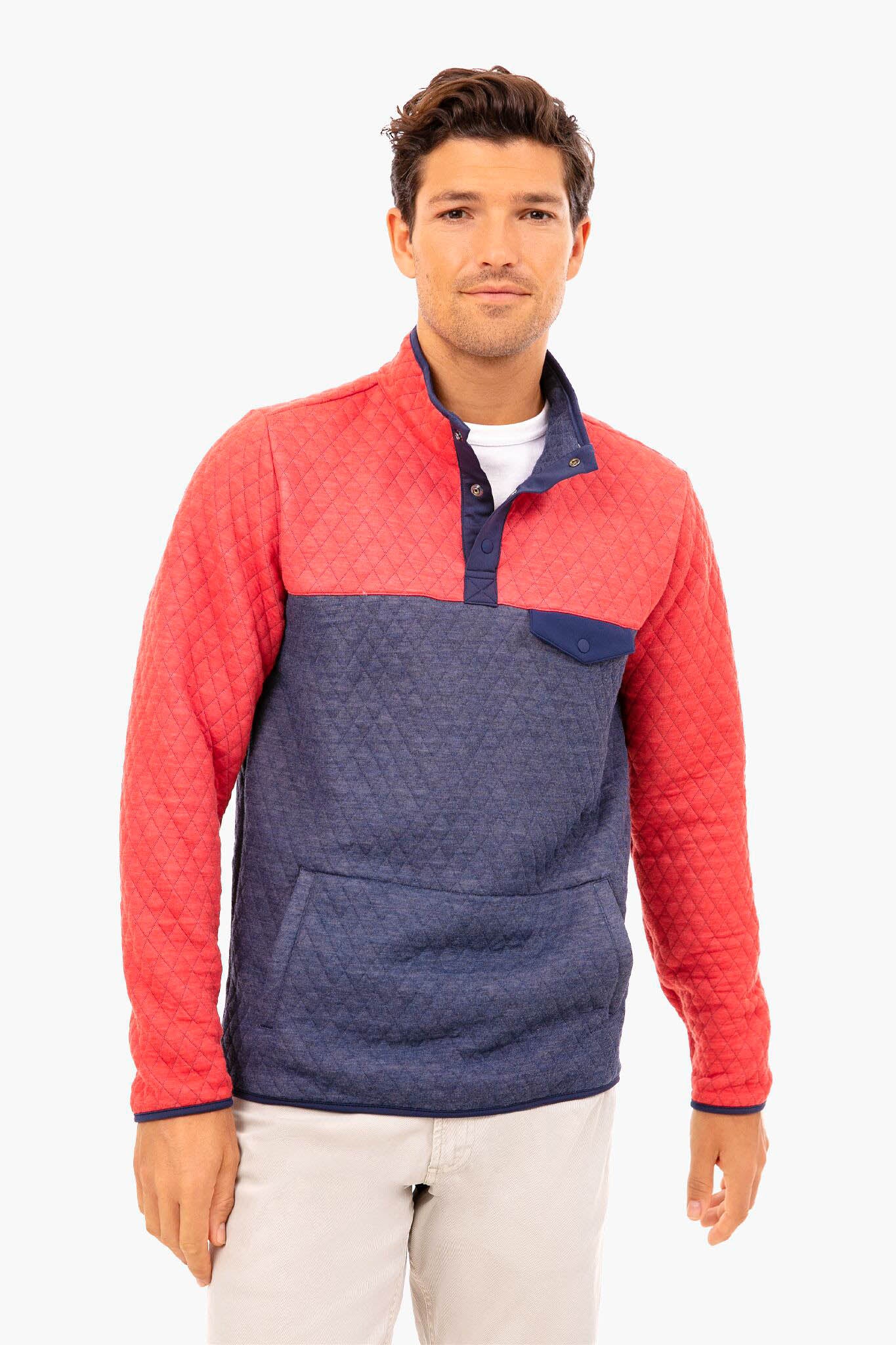 A man in a Marine Layer sustainably-made quilted pullover featuring a red upper and sleeves, blue lower section, and a front pocket.