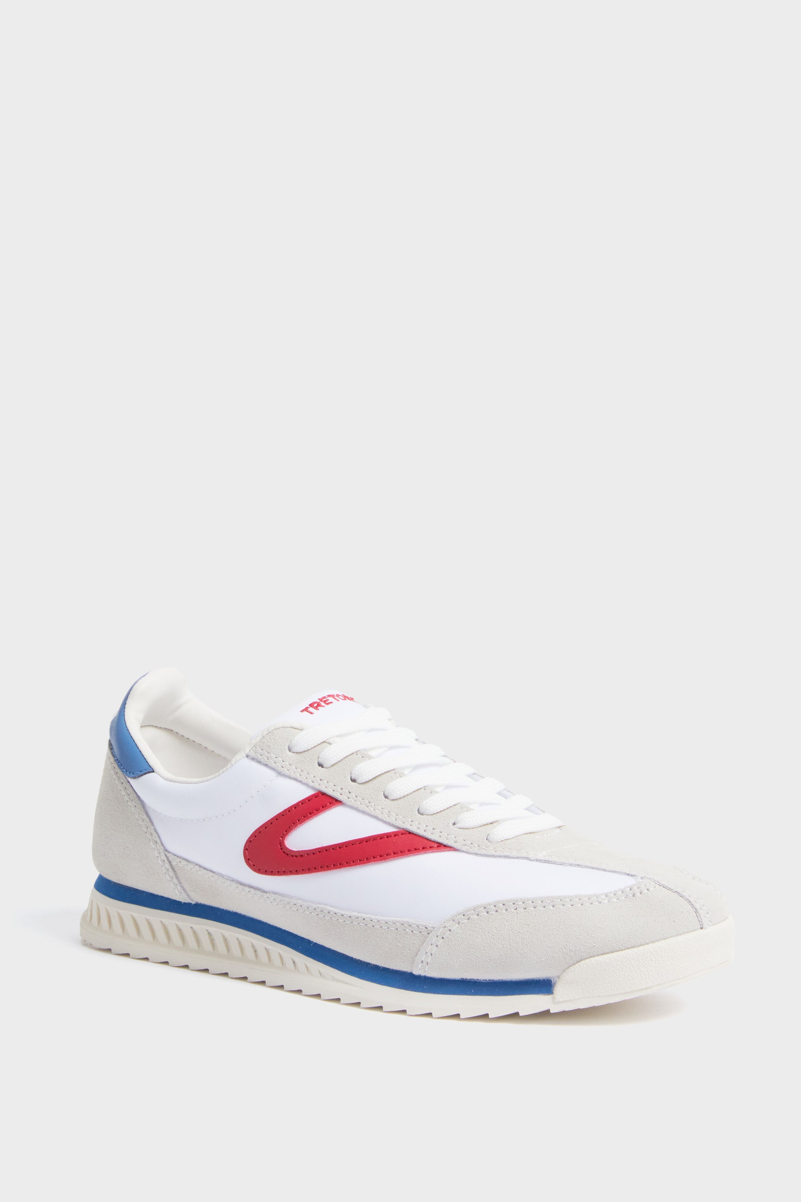 A Tretorn women's Rawlins sneaker in white features beige suede details, a red side accent, blue heel trim, white laces, and a textured rubber sole.