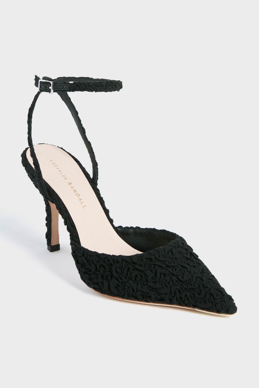 A black pointed-toe high heel from Loeffler Randall with an adjustable ankle strap and textured fabric, featuring the elegant Black Puckered Jaden Heels.