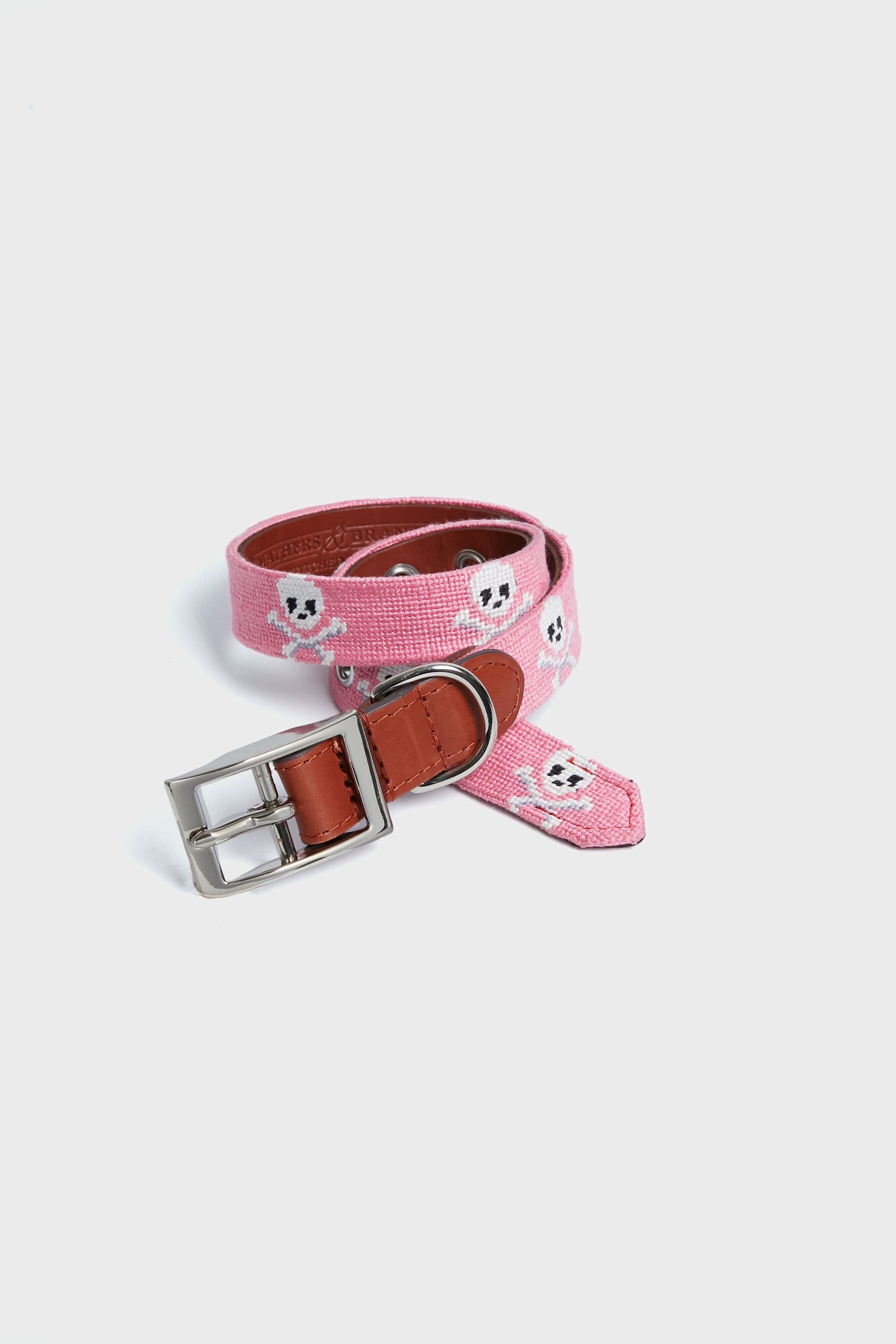 A Smathers and Branson pink needlepoint dog collar features white skull patterns, brown leather accents, and a silver buckle.