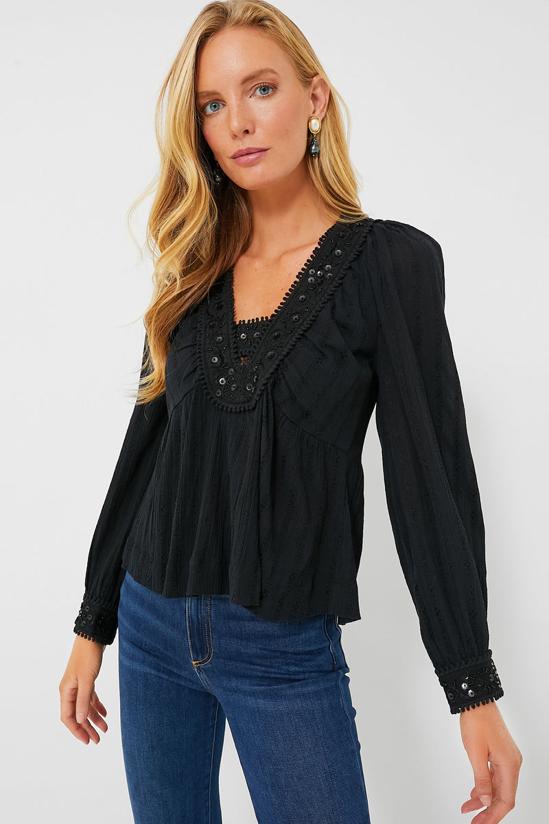 A woman with long blonde hair wears the Sea New York Charlotte Embroidery Top, featuring lace, button details, and sequin embroidery, styled with blue jeans.
