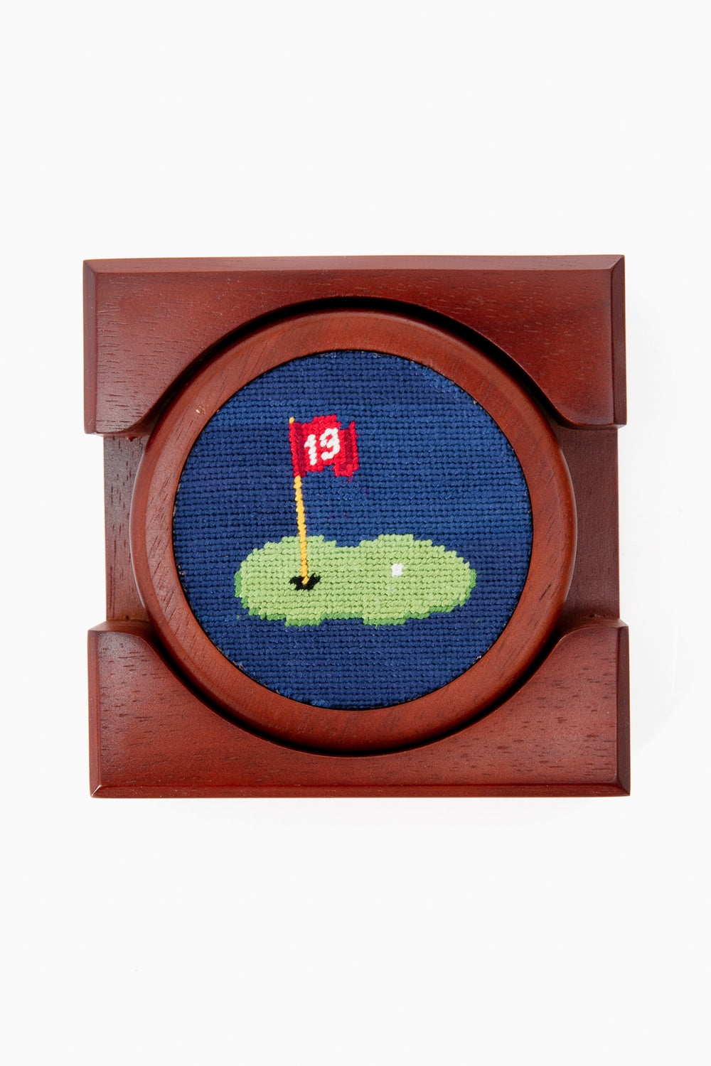 A Smathers and Branson wooden needlepoint coaster featuring a hand-stitched golf hole with a red flag labeled 13 and white golf ball—perfect as a unique golf gift.