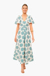 Woman wears a La DoubleJ vintage-inspired white maxi dress with blue floral patterns, short flutter sleeves, and a v-neckline. She styles it with strappy sandals and simple jewelry for effortless elegance.