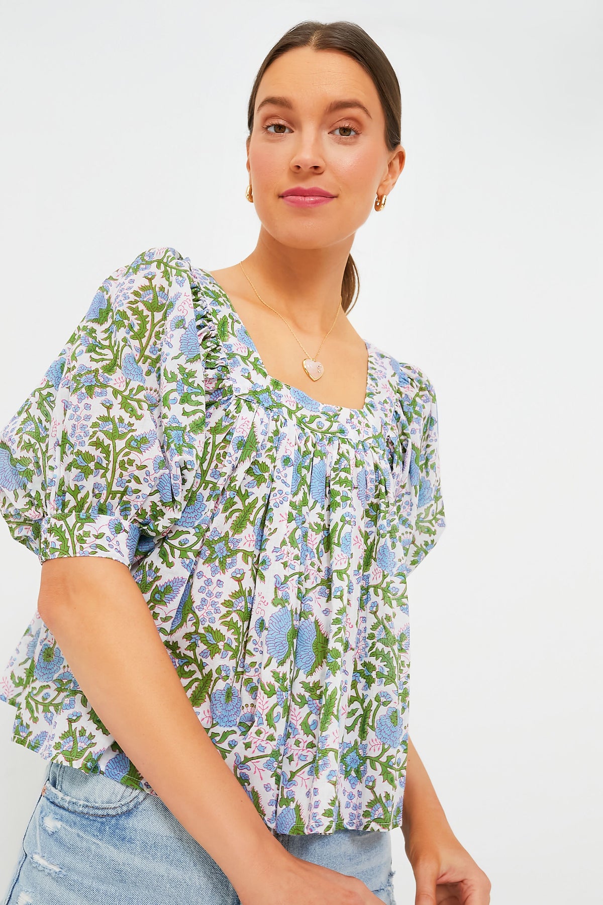 A woman models a stylish SZ Blockprints top with puffed sleeves and a floral block print, paired with light blue denim jeans.