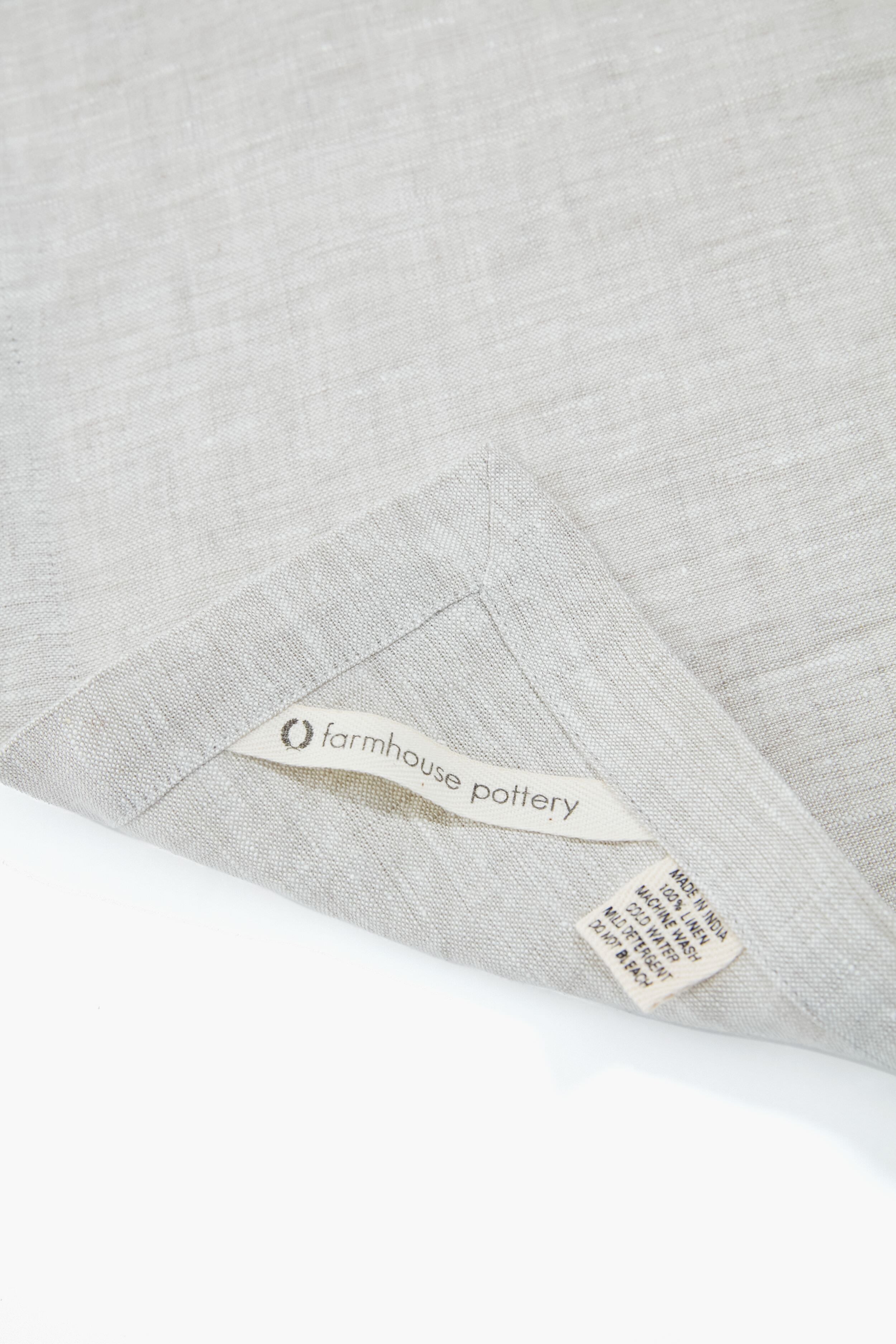 Stone Washed Linen Napkins from Farmhouse Pottery, classic and effortlessly chic, showcasing a folded corner and tags. Made in India, high-end and fun for any dining occasion.