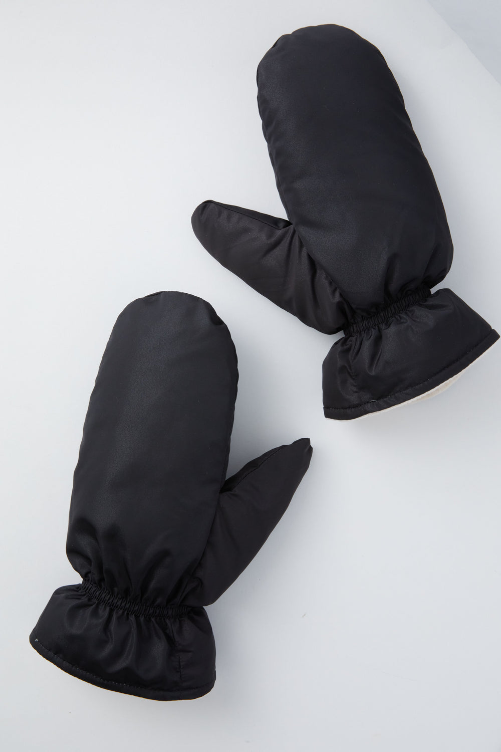 A pair of Hat Attack black fleece-lined mittens with elastic wrists are displayed on a light gray surface.
