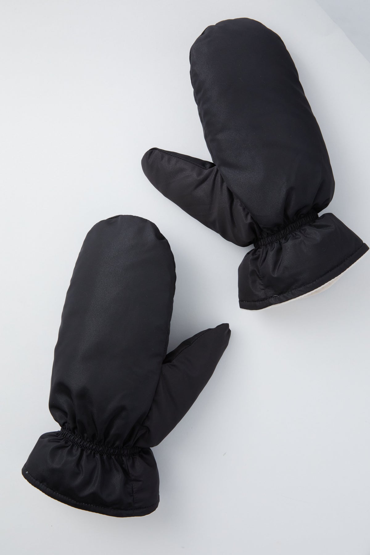 A pair of Hat Attack black fleece-lined mittens with elastic wrists are displayed on a light gray surface.