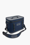 A YETI navy blue waterproof cooler featuring a zippered lid, top handle, side loops, and an adjustable shoulder strap.