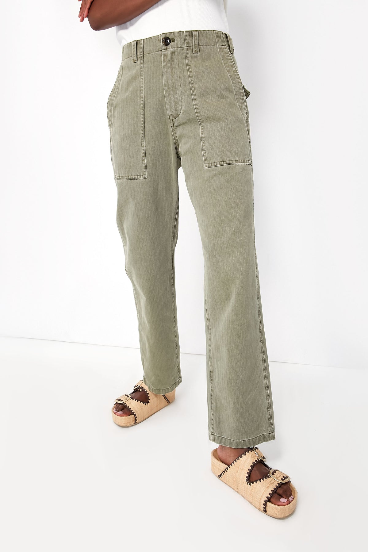 A woman showcases casual style in Alex Mill vintage olive herringbone utility pants with large front pockets and beige platform sandals.
