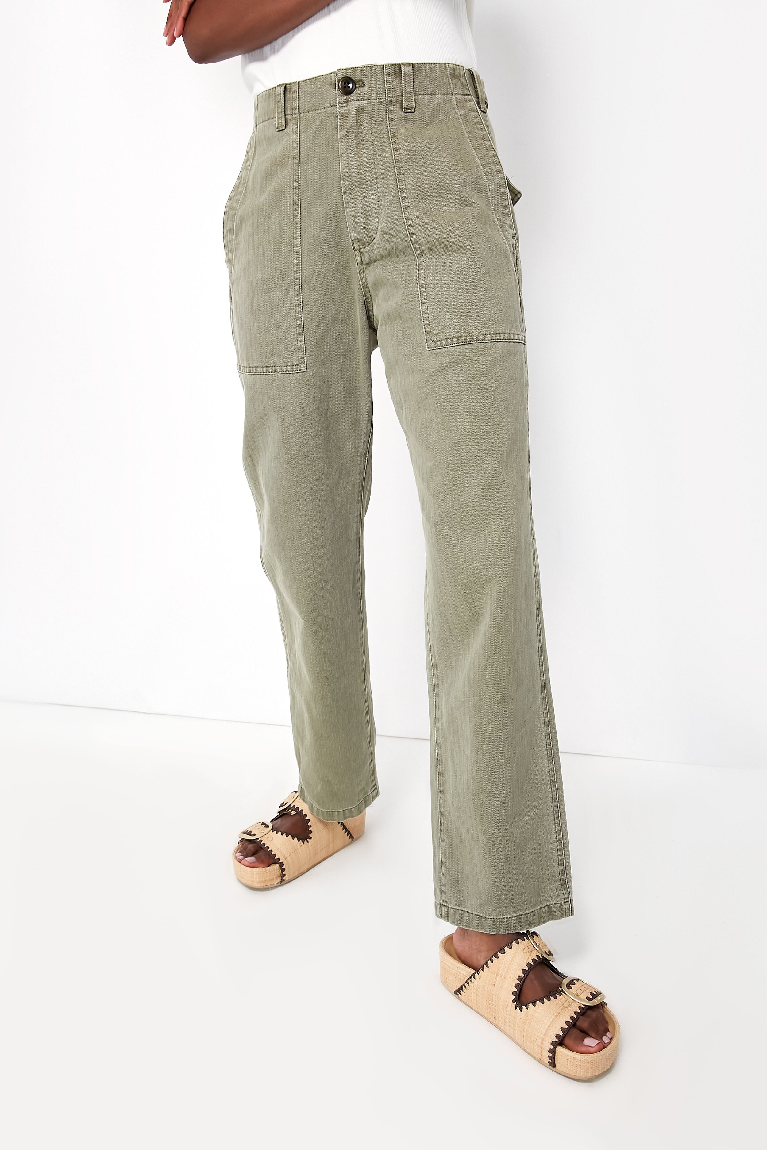 A woman showcases casual style in Alex Mill vintage olive herringbone utility pants with large front pockets and beige platform sandals.