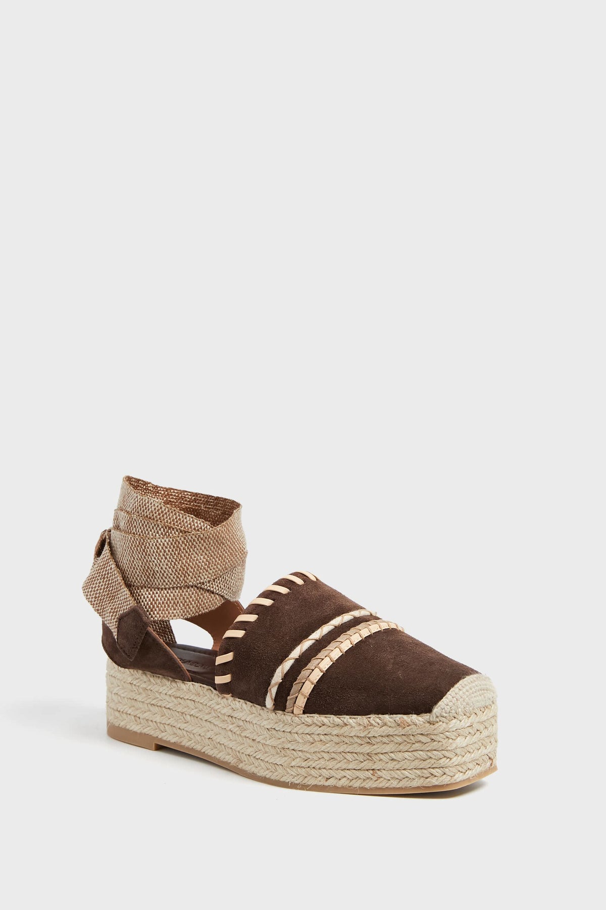 The Ulla Johnson brown suede espadrille features a thick jute platform sole, decorative stitching, and lace-up tan ankle ties.