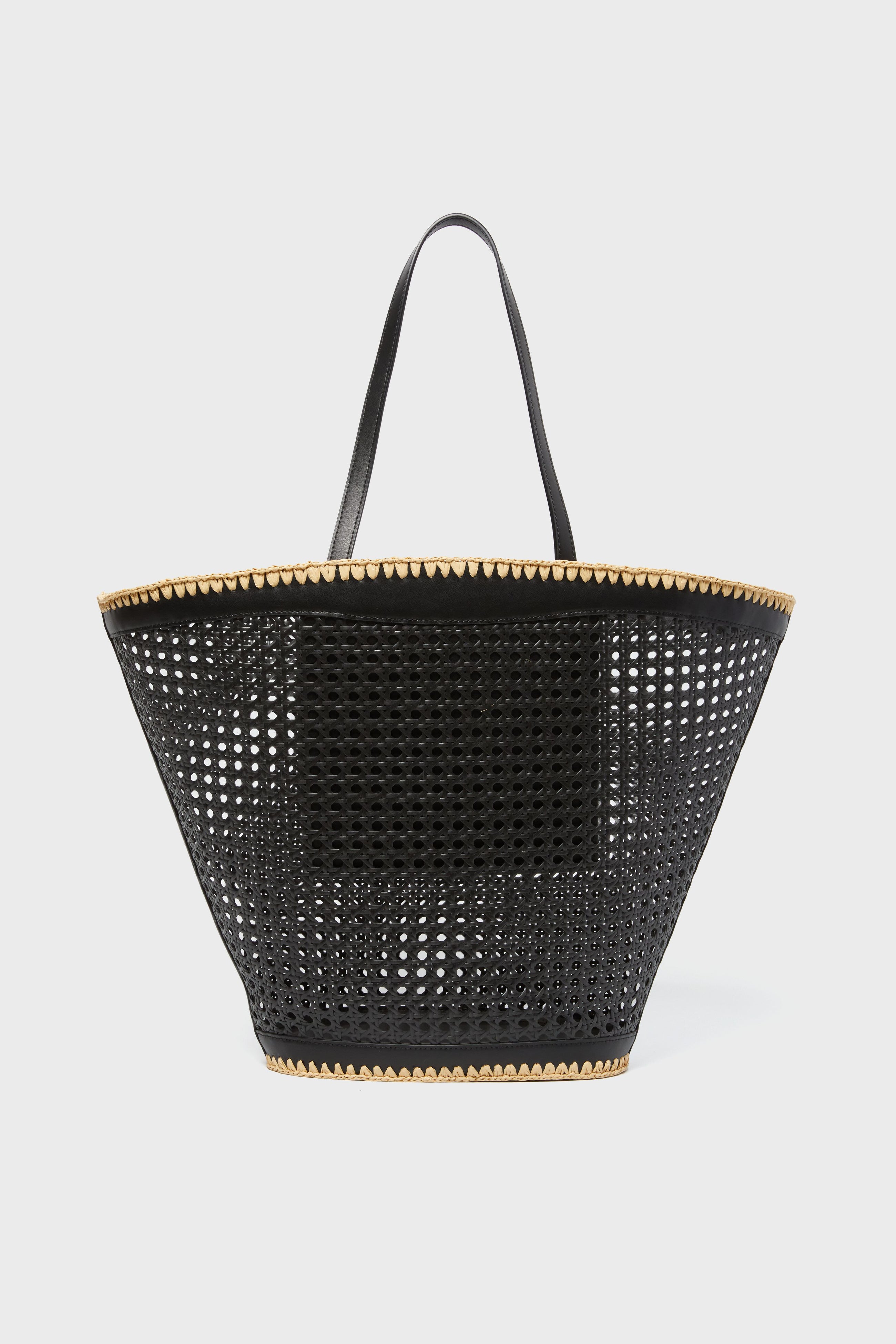 A black perforated BTB Ellie Tote with two handles and tan trim at the top and bottom—perfect for adding a boho-chic accent to any outfit.