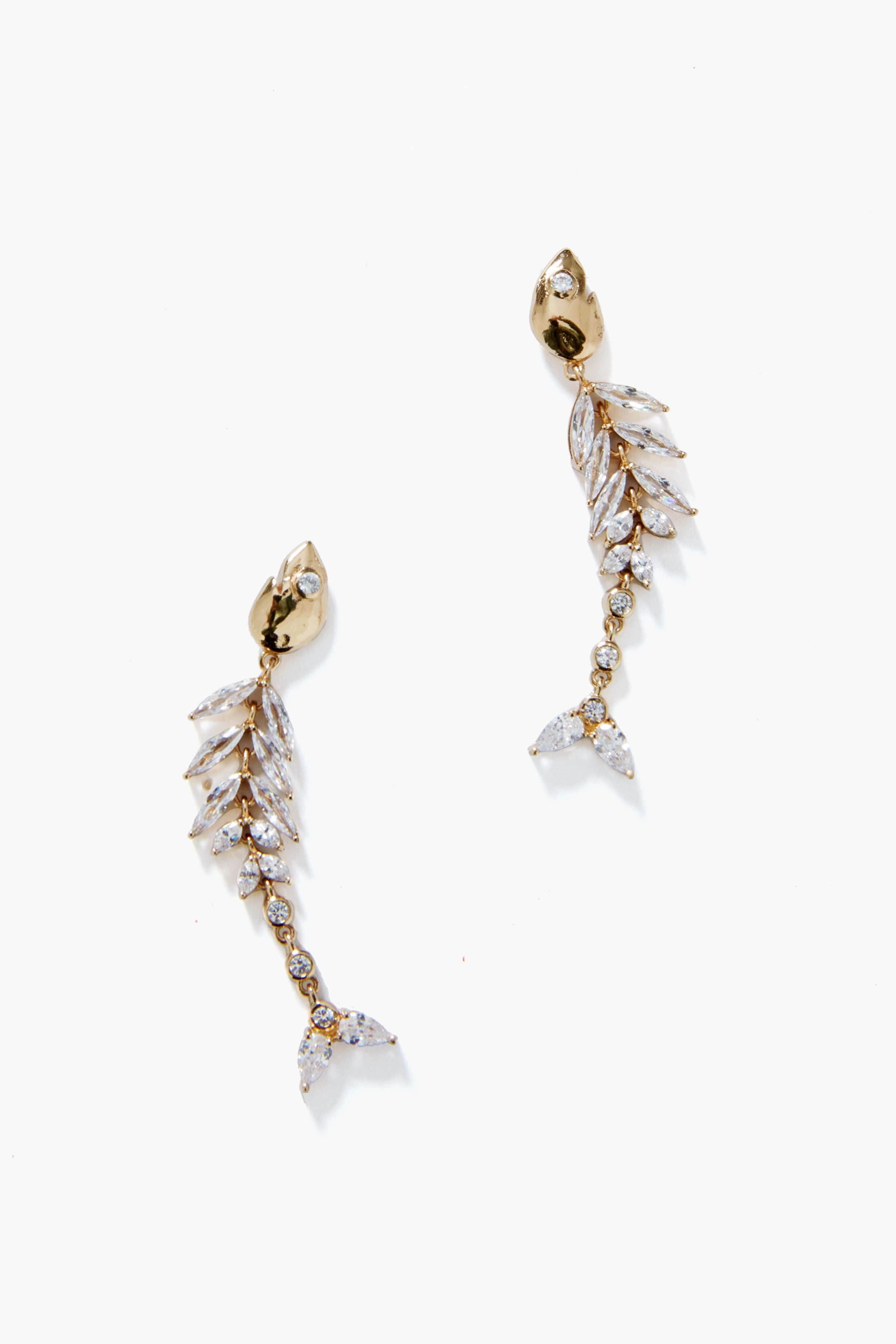 Mignonne Gavigan's 14K gold plated Elisabetta Fish Earrings feature a fish skeleton shape adorned with clear gemstones on the spine, fins, and tail—a unique jewelry piece that stands out.