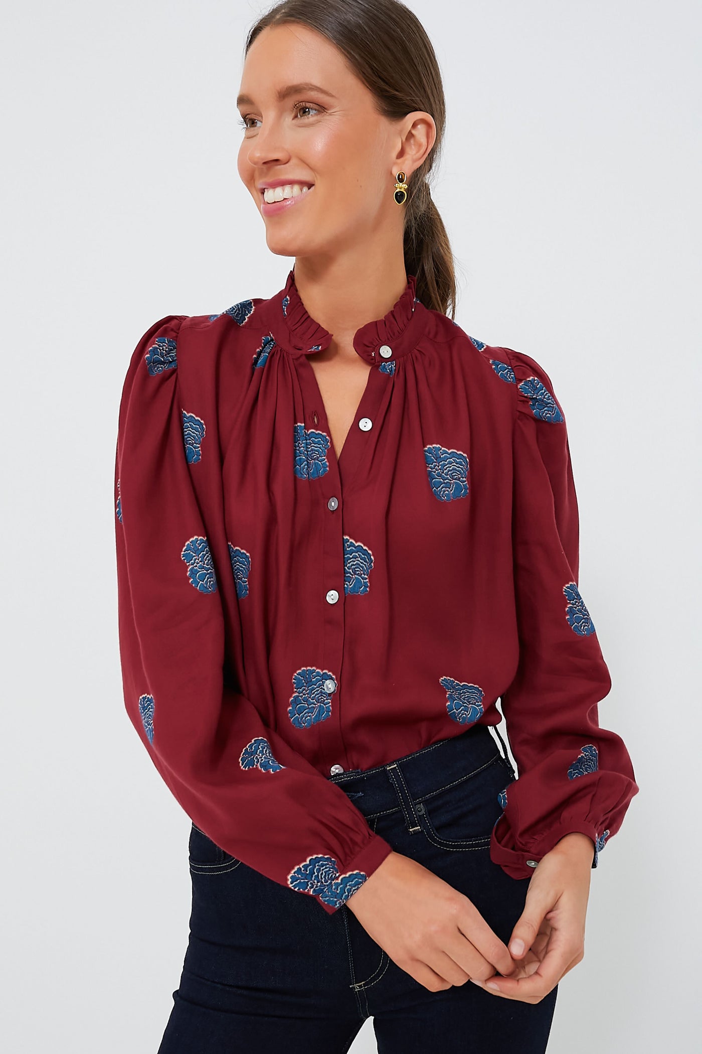 Person wearing an Alix of Bohemia Red Burgundy Annabel Shirt with blue floral patterns, smiling and gazing slightly to the side.