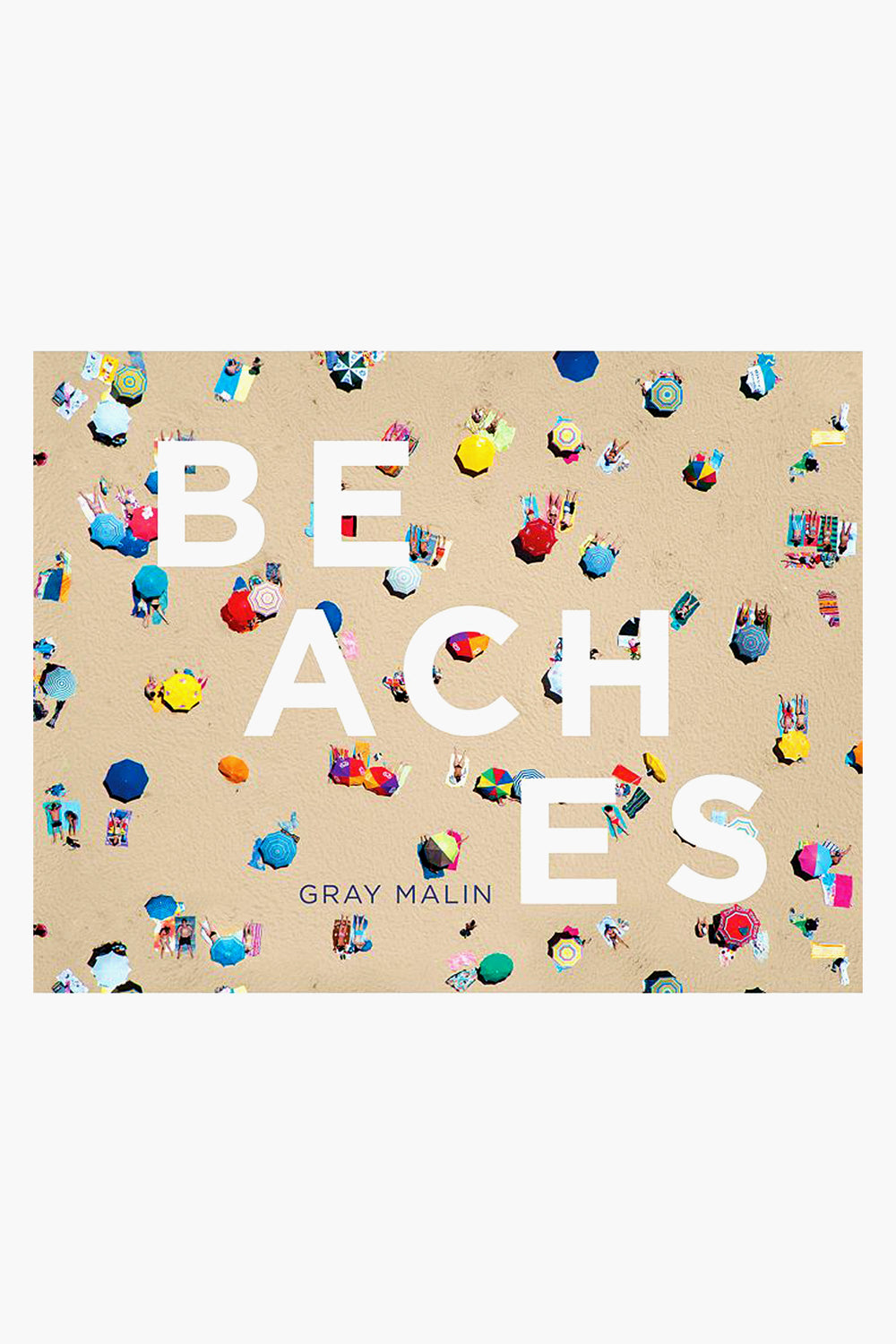 Aerial view of a crowded sandy beach with colorful umbrellas and towels, overlaid with large white text reading BEACHES and Gray Malin's name below—an eye-catching Rizzoli coffee table book featuring stunning aerial beach photography.