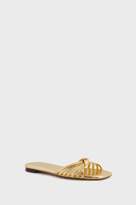 A flat, open-toe sandal from Loeffler Randall in gold metallic, featuring multiple thin straps and a chic knotted design.