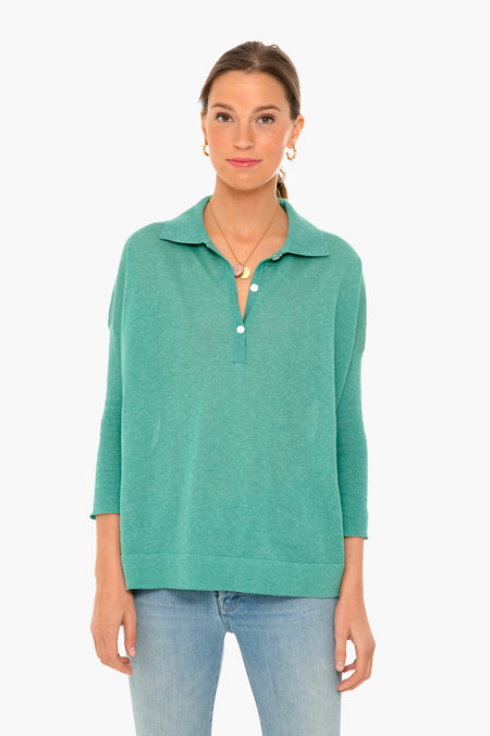 A woman wears a Tuckernuck teal Clayton Polo in featherweight knit with a classic collared, buttoned style and light blue jeans.