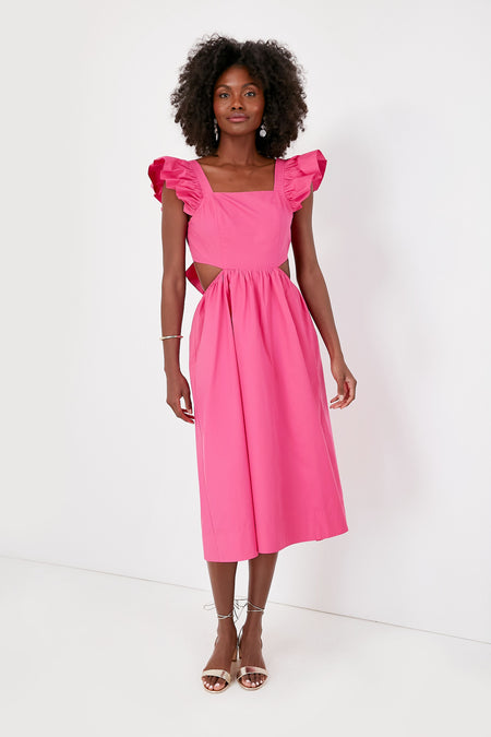 A woman wears the Hyacinth House Aspyn Dress, a fuchsia midi with ruffle sleeves and side cutouts, paired with strappy sandals.