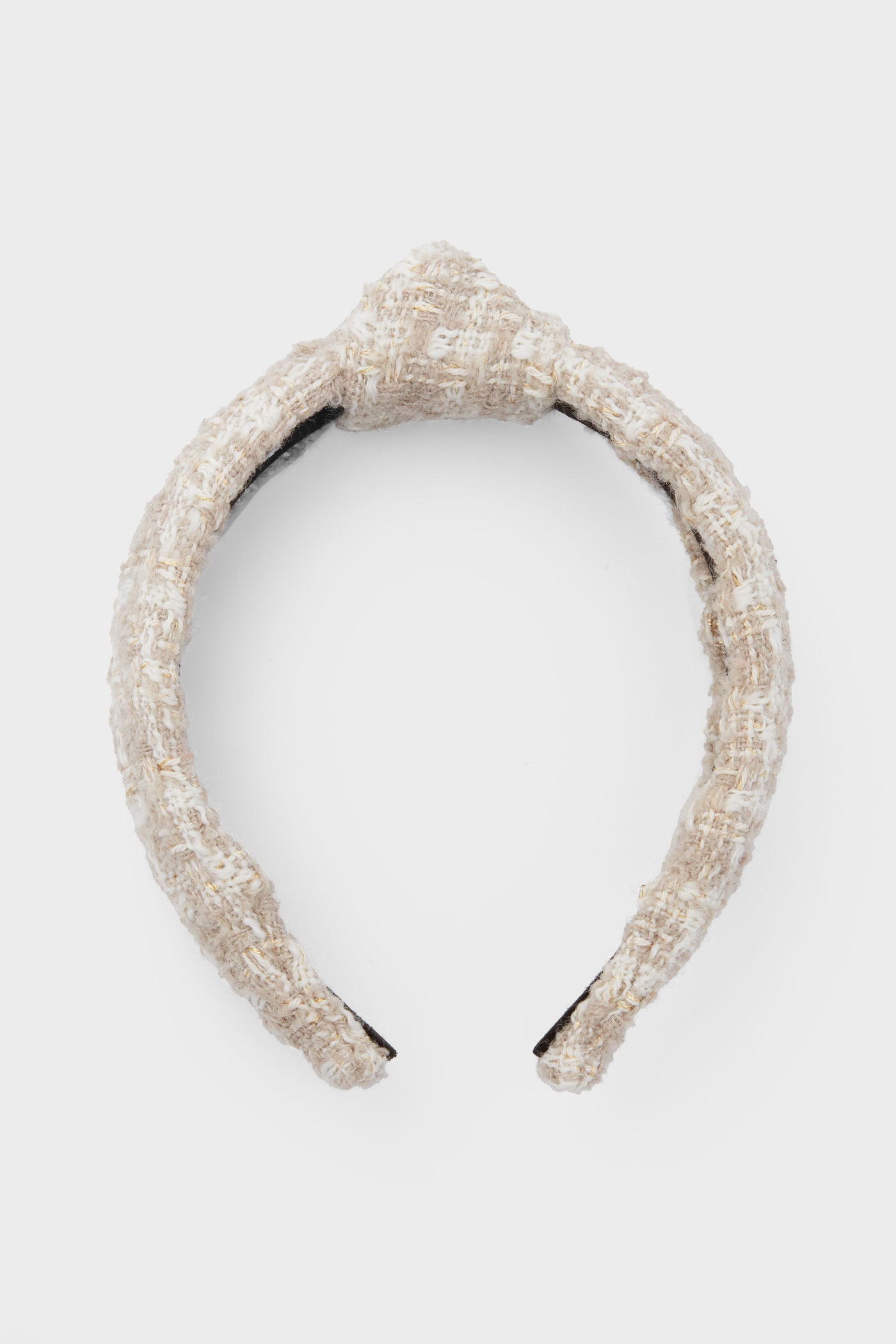 A beige tweed headband by Lele Sadoughi features a textured design with a central knot, inspired by the brand's signature style.