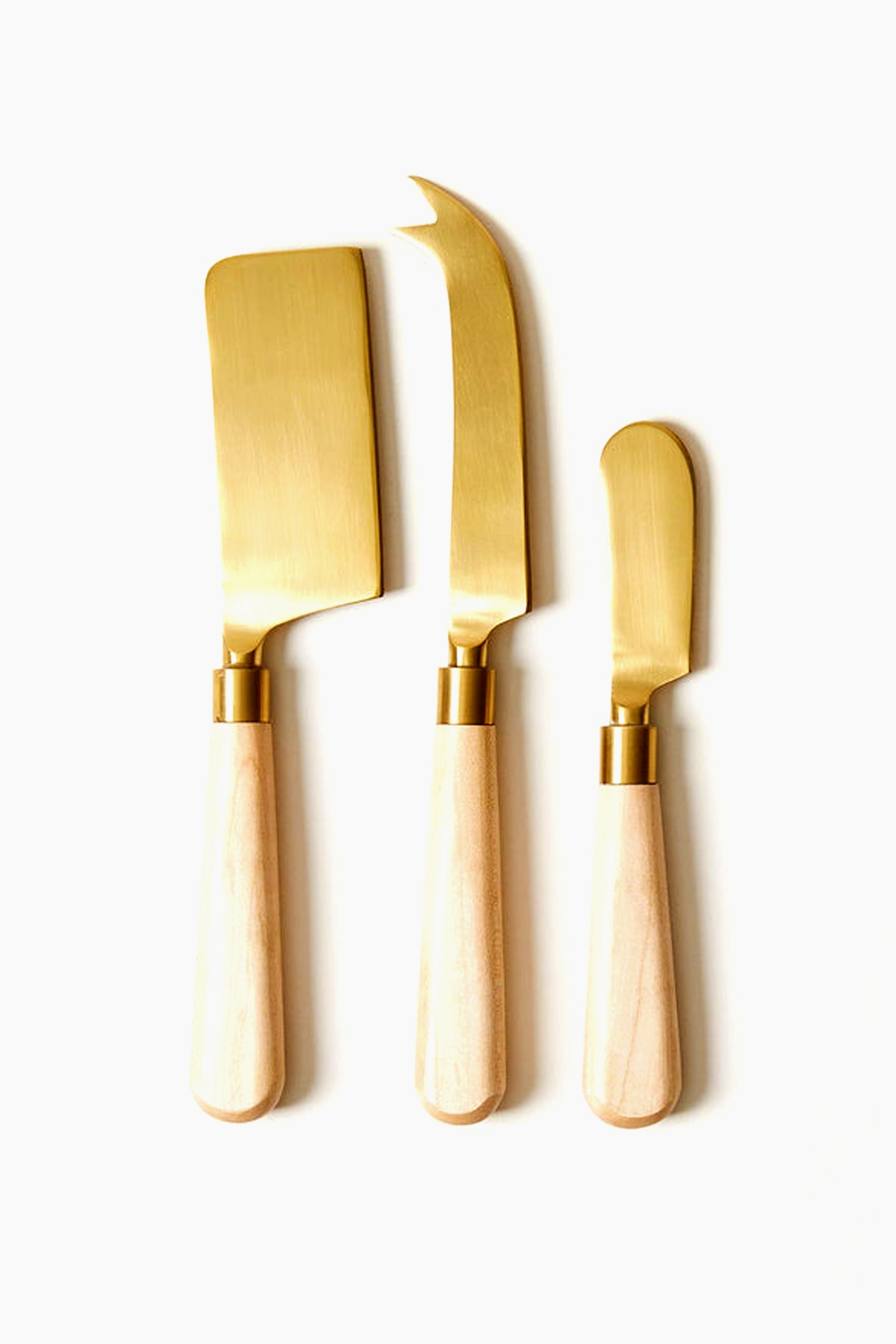 The Farmhouse Pottery, Inc cheese knife set includes three gold knives with handcrafted wooden handles, arranged side by side—perfect for adding a touch of farmhouse charm to your entertaining.
