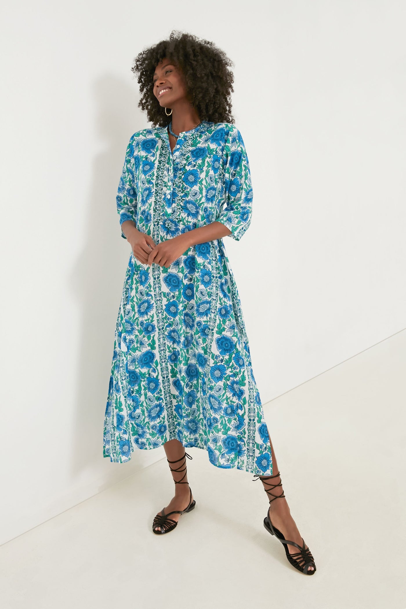 A woman wears a Ro's Garden Blue Dijon Classic Long Kurta, styled as a floral midi dress with three-quarter sleeves and black lace-up sandals—perfect luxury travel wear.