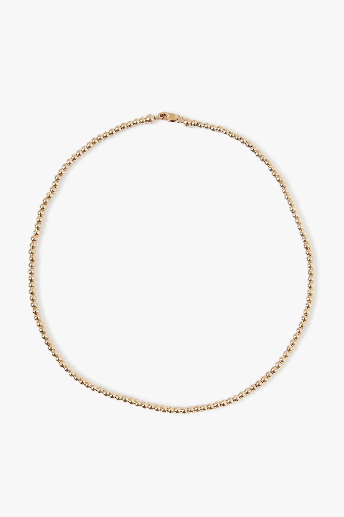 A delicate Alexa Leigh 14k gold plated beaded necklace with a small clasp, arranged in a circular shape—perfect for layering or wearing solo as a gold ball necklace.