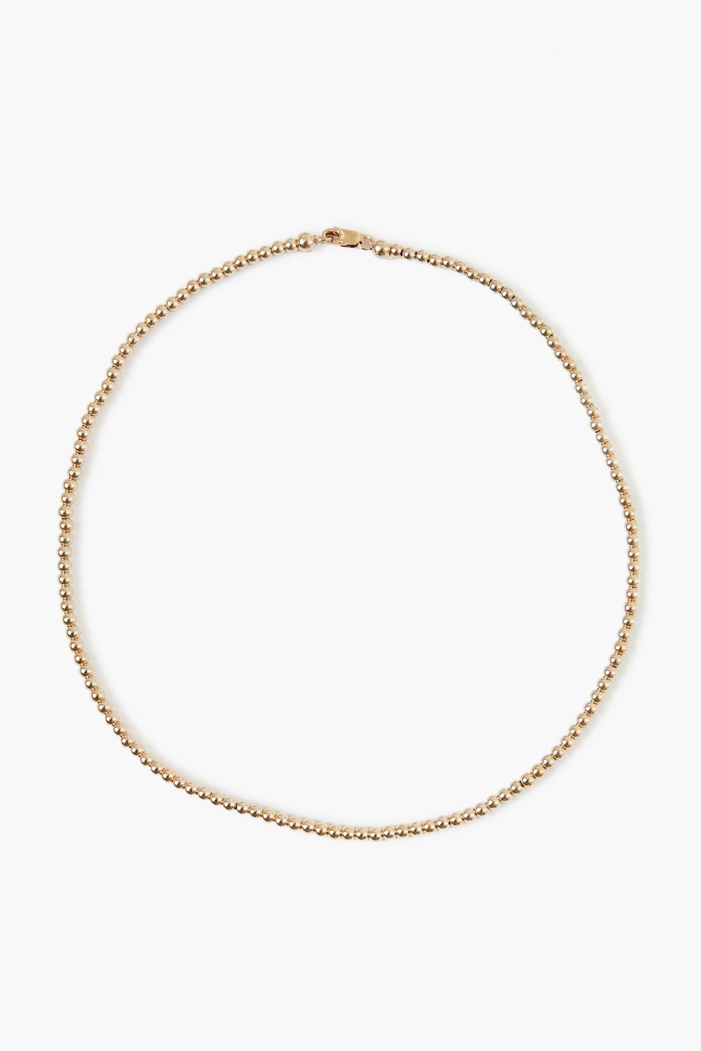 A delicate Alexa Leigh 14k gold plated beaded necklace with a small clasp, arranged in a circular shape—perfect for layering or wearing solo as a gold ball necklace.