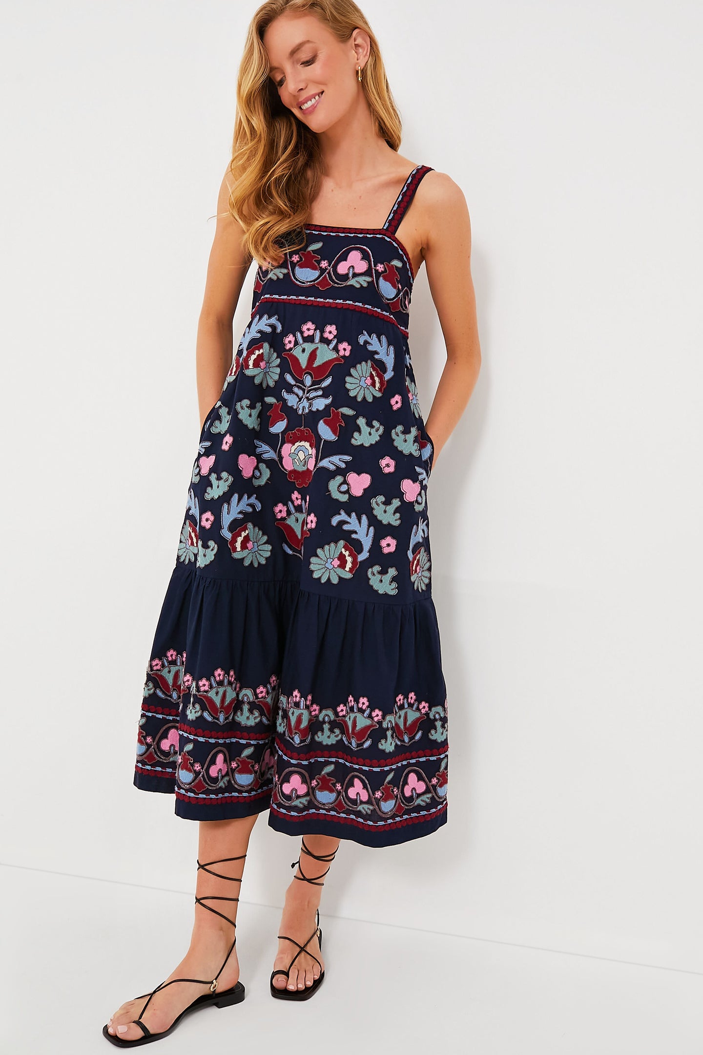 Woman in a navy blue slip dress by Sea New York featuring colorful floral embroidery, paired with black lace-up sandals.